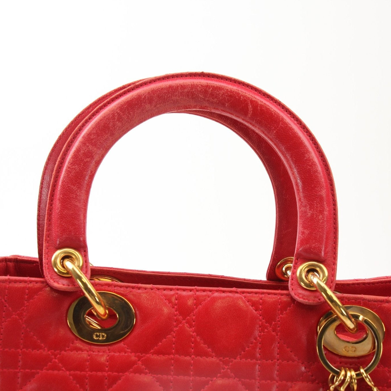 Red Christian Dior Lady Dior handbag with top handle, featuring signature design and elegant gold accents.