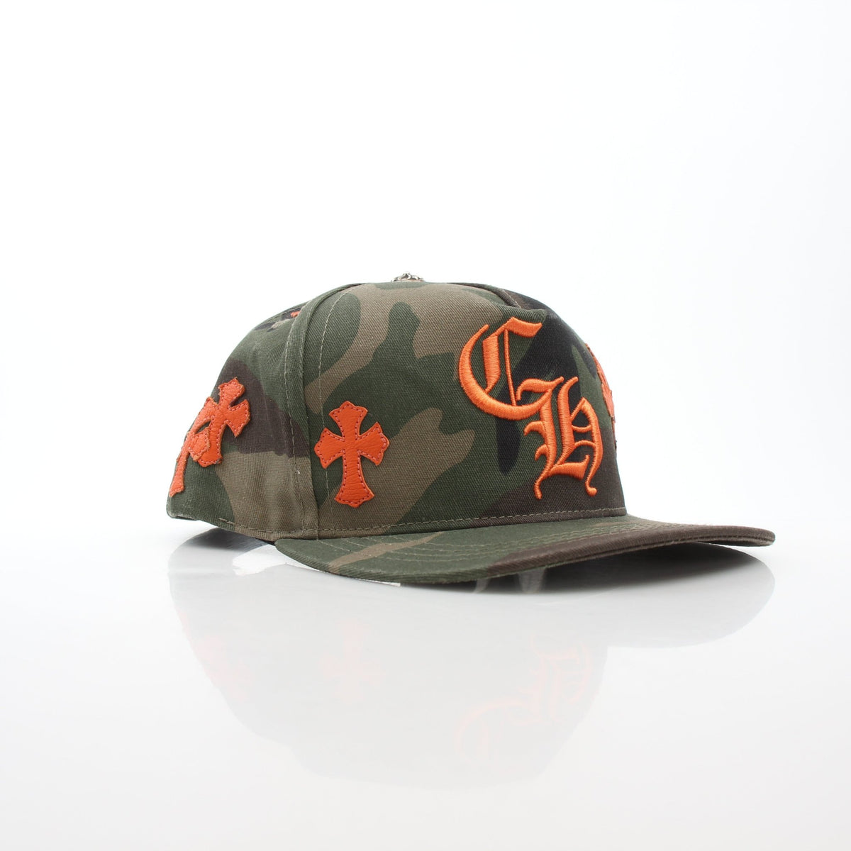 Chrome Hearts Camo Orange Cemetery Cross patch on a Gold & Beyond baseball hat, close-up view of the embroidered accessory.