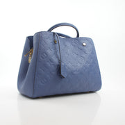 Louis Vuitton Montaigne MM Monogram Empreinte leather handbag in blue with gold hardware and structured design.