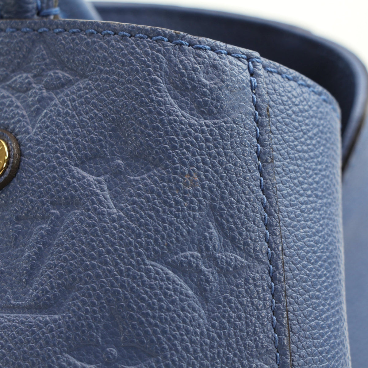 Blue Louis Vuitton Montaigne MM Monogram Empreinte leather handbag with gold hardware and structured design.