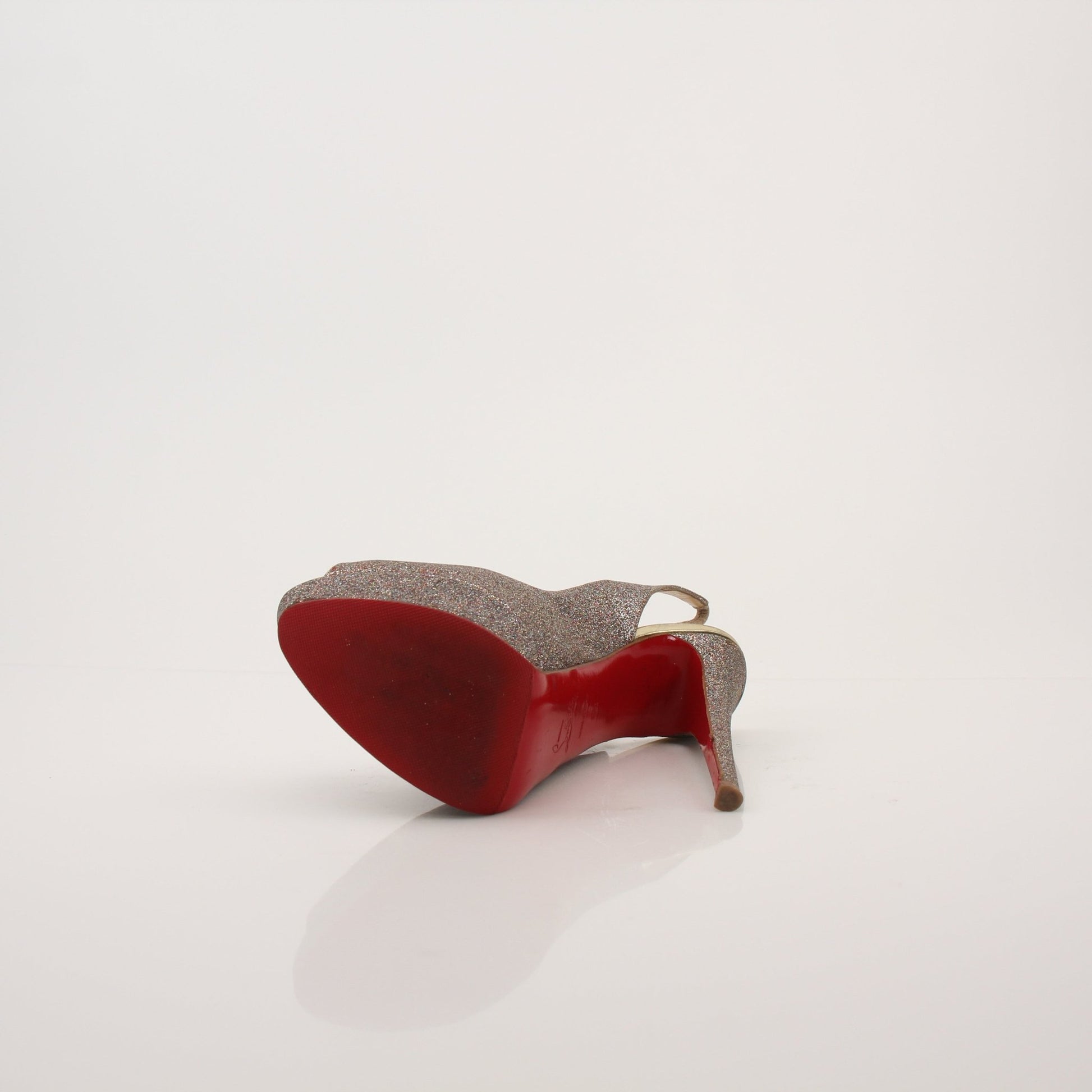 Gold & Beyond Christian Louboutin glitter slingback heels with pointed toes and stiletto heels on a neutral background