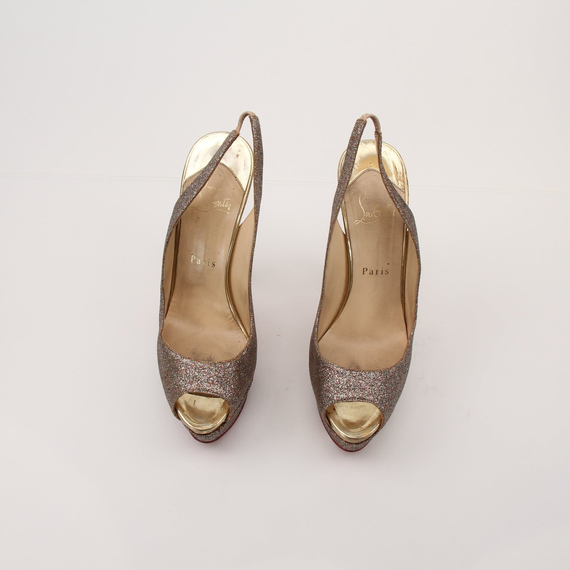 Christian Louboutin glitter slingback heels with pointed toes and signature red soles, featuring sparkling embellishments.