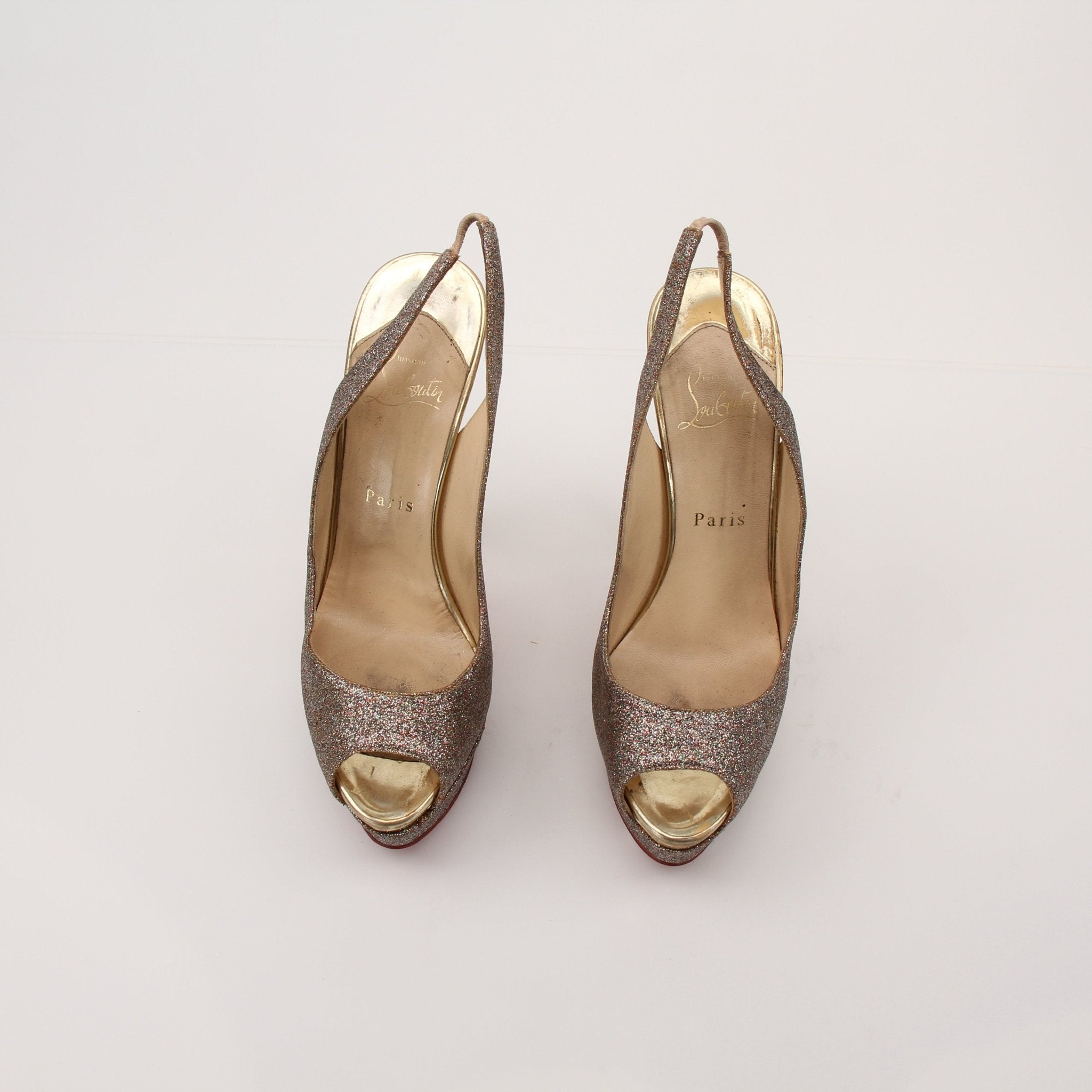 Christian Louboutin glitter slingback heels with pointed toes and signature red soles, featuring sparkling embellishments.