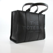 Black leather Marc Jacobs large tote handbag with structured design and top handles, stylish and spacious for everyday use.