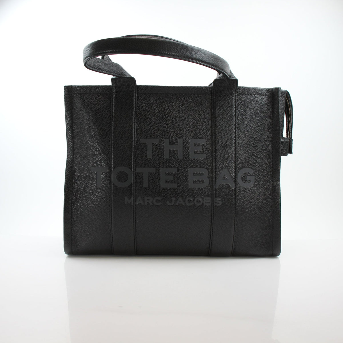 Black Marc Jacobs The Leather large tote handbag with structured design and top handles, shown against a neutral background.