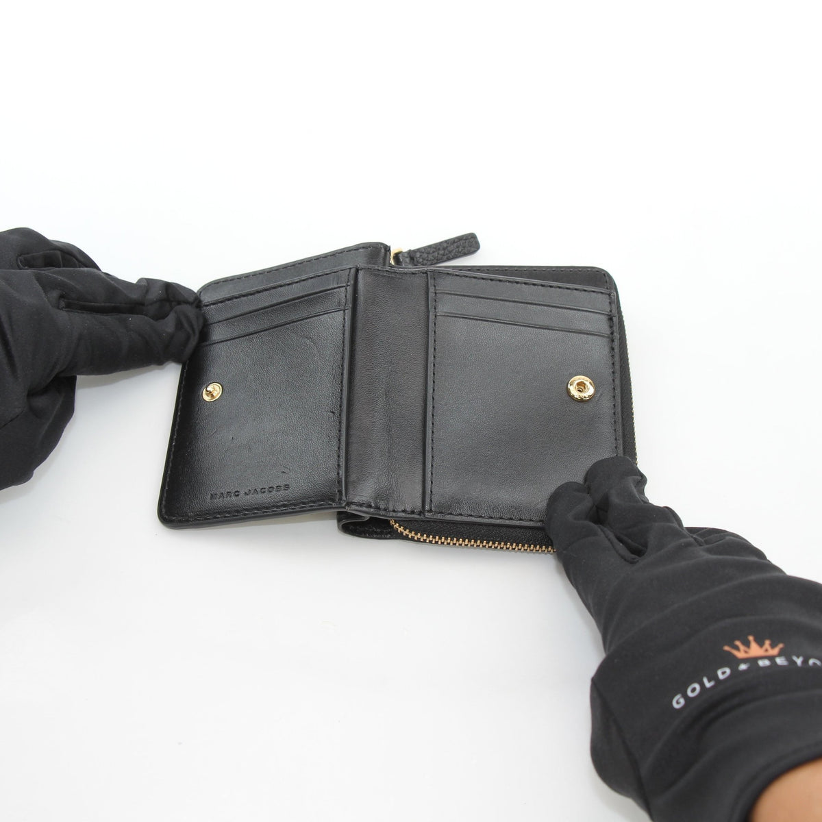Black Marc Jacobs leather mini compact wallet with gold accents, showcasing its sleek, compact design and high-quality craftsmanship.