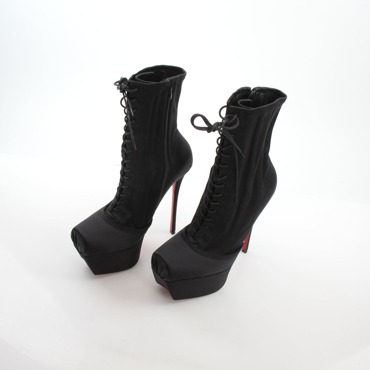 Christian Louboutin Pavlova Booty Alta black satin platform heels with high stiletto heels and pointed toes.