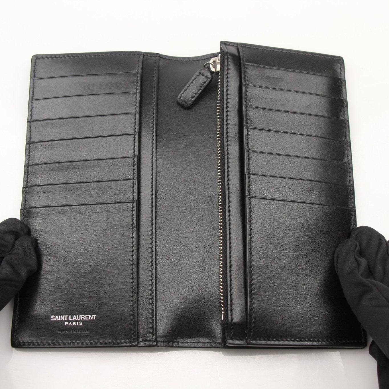 Black Saint Laurent Monogram YSL flap wallet with gold-tone hardware and stitched detailing, featuring the iconic YSL logo.