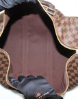 Louis Vuitton Keepall 50 Damier Ebene duffle bag with leather trim, featuring signature checkered pattern and sturdy handles.