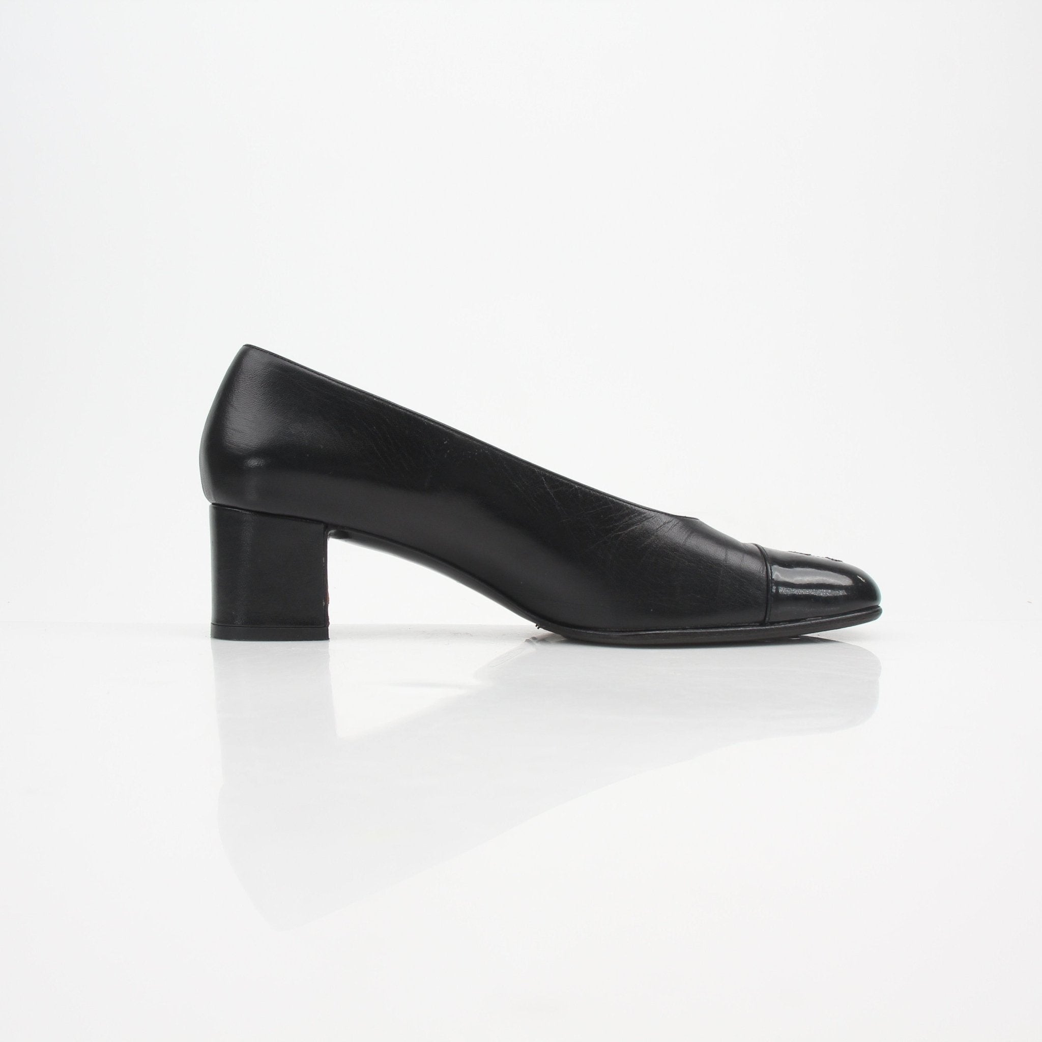 Gold & Beyond Chanel Cap Toe CC block heel pumps with black leather shoes and signature front detailing, showcasing elegant footwear design.