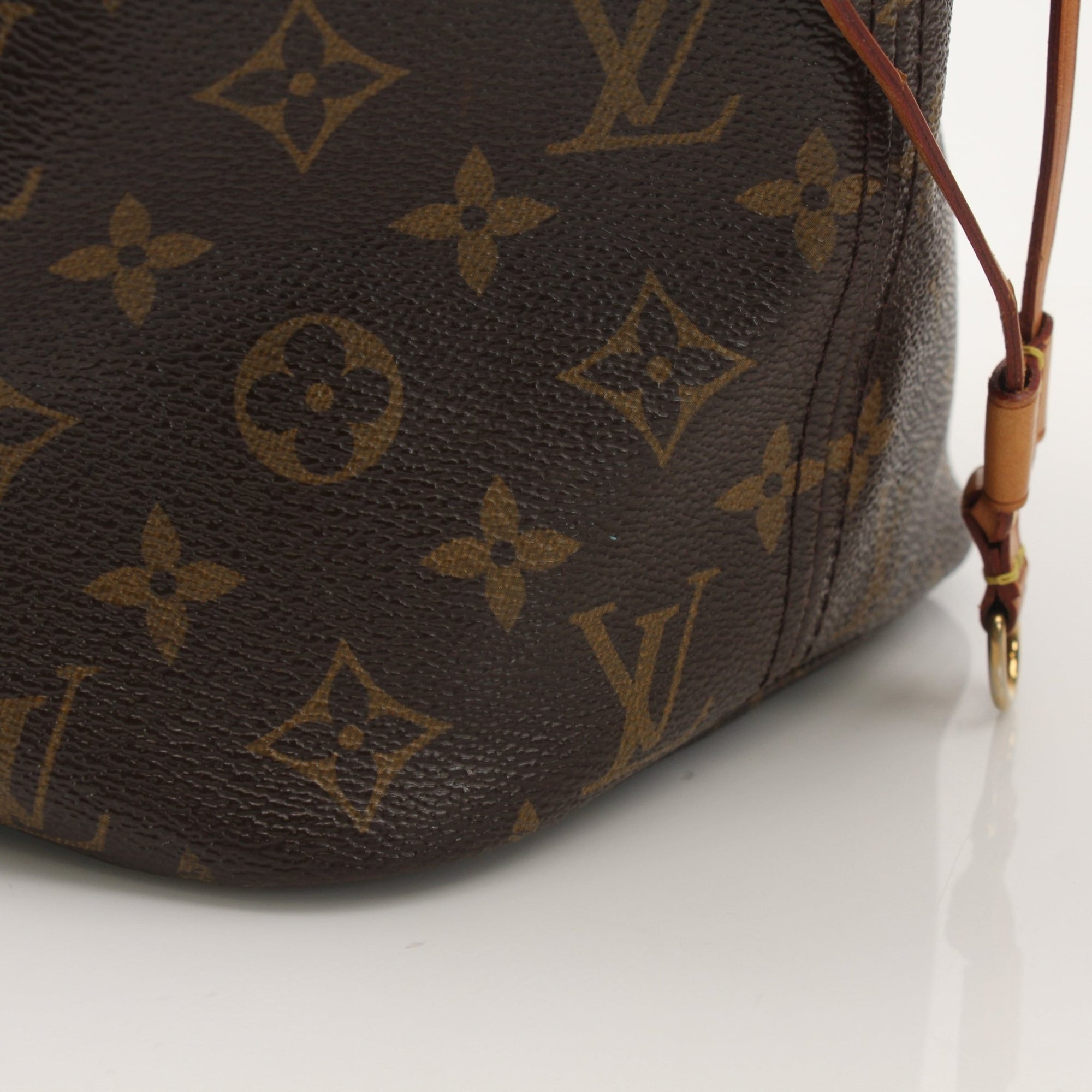 Louis Vuitton Neverfull Monogram tote handbag with gold accents, displayed on a neutral background.