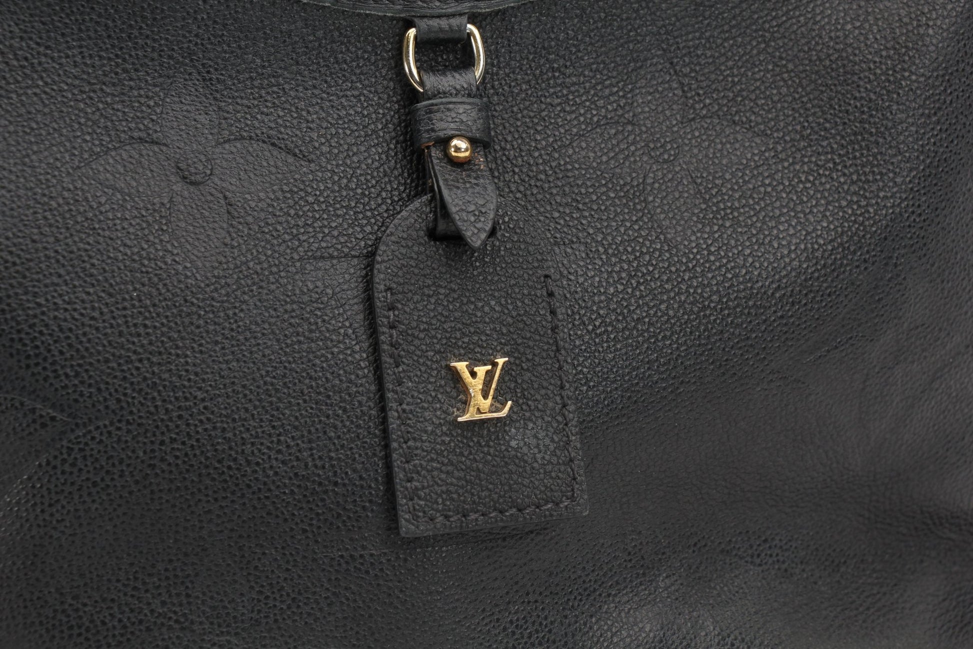 Louis Vuitton Carryall PM handbag in gold with structured design and top handles, showcased in a stylish setting.