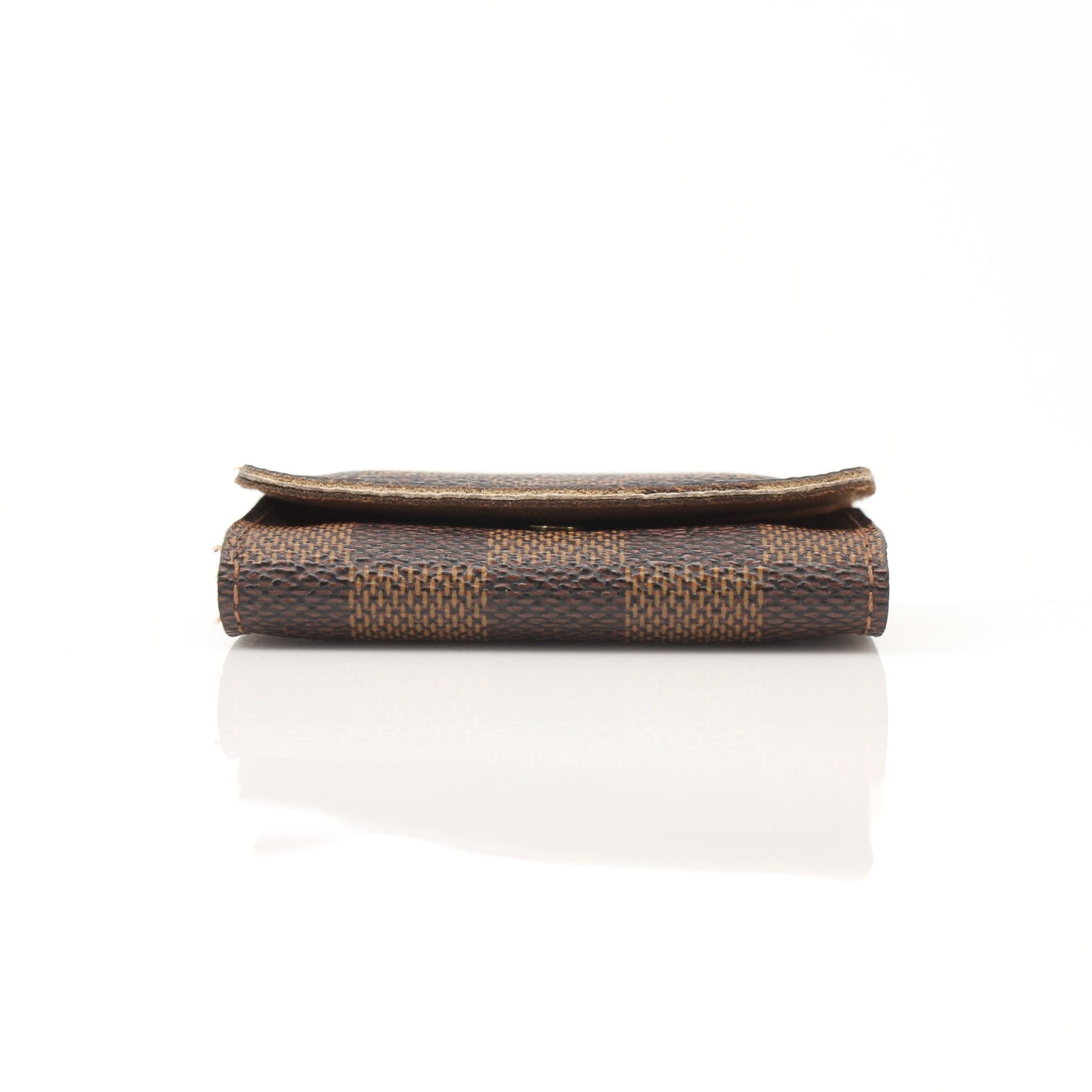 Louis Vuitton Damier Ebene key holder pouch with gold accents, featuring a checkered pattern and compact accessories design.