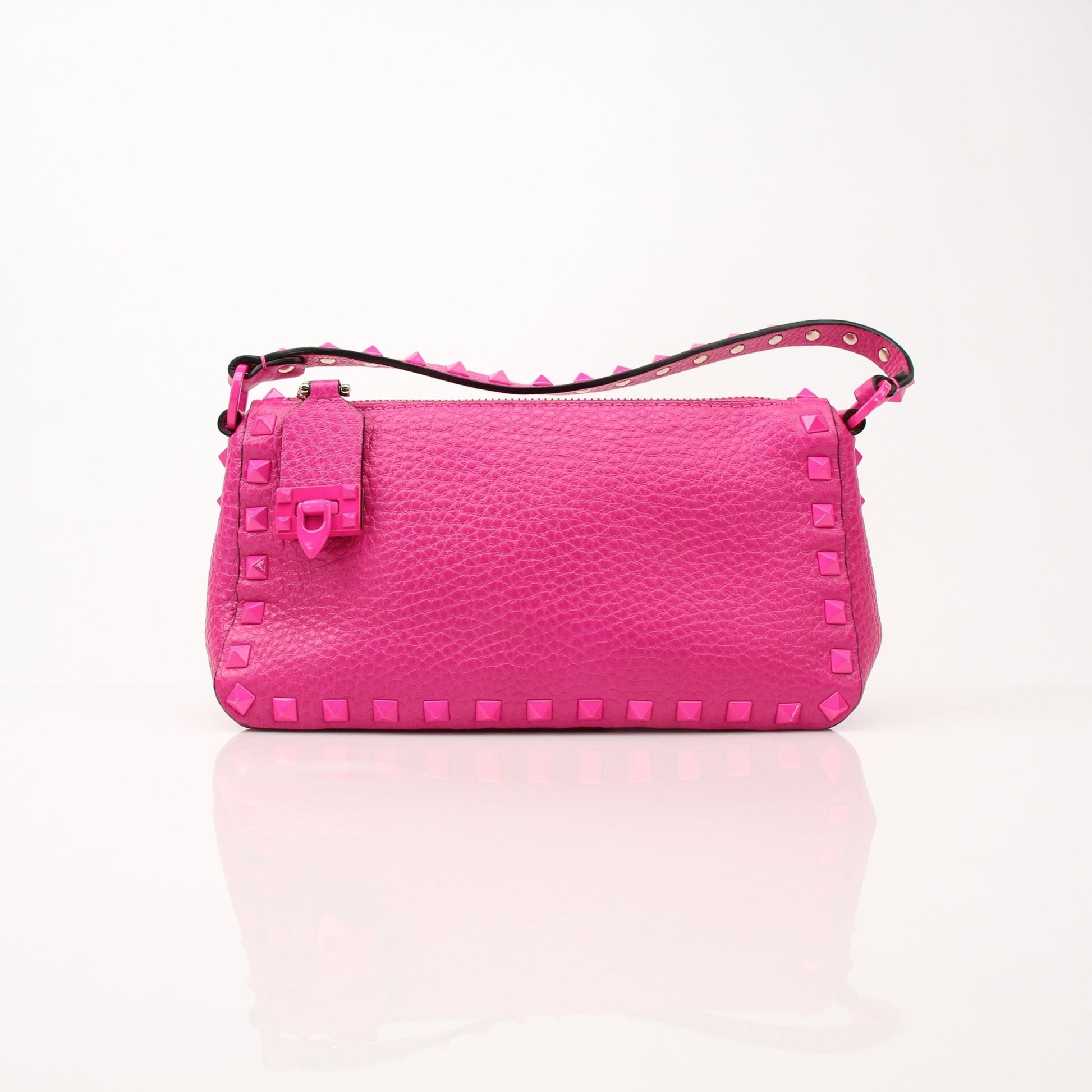 Fuchsia pink Valentino Rockstud flip lock shoulder handbag with gold hardware and stud accents, held by a person.