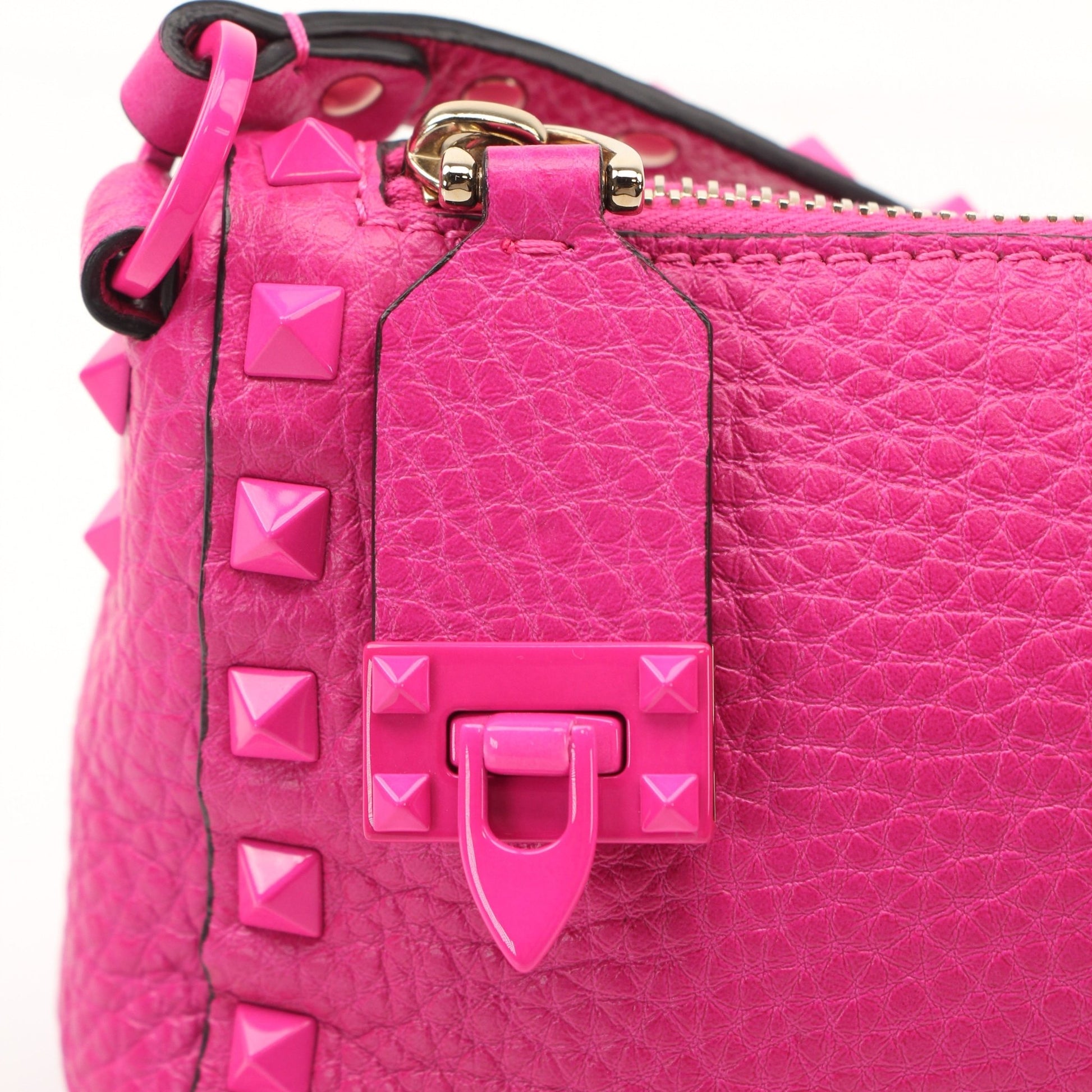 Fuchsia pink Valentino Rockstud flip lock shoulder handbag with gold accents and stud details, stylishly displayed.