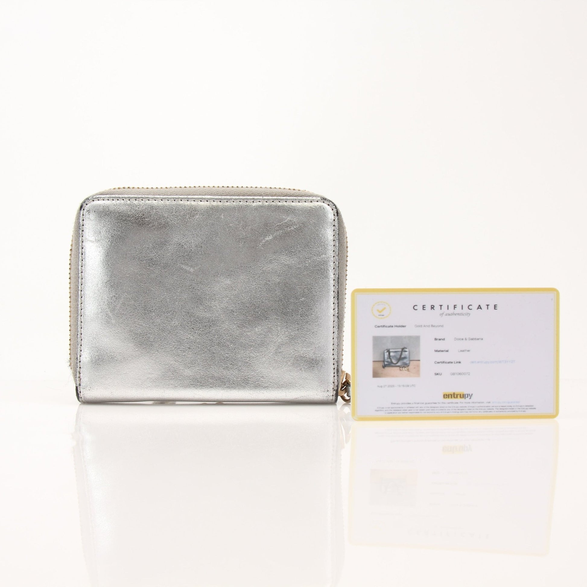 Dolce & Gabbana metallic silver zip-around wallet with gold accents, showcasing its sleek, shiny finish and compact design.