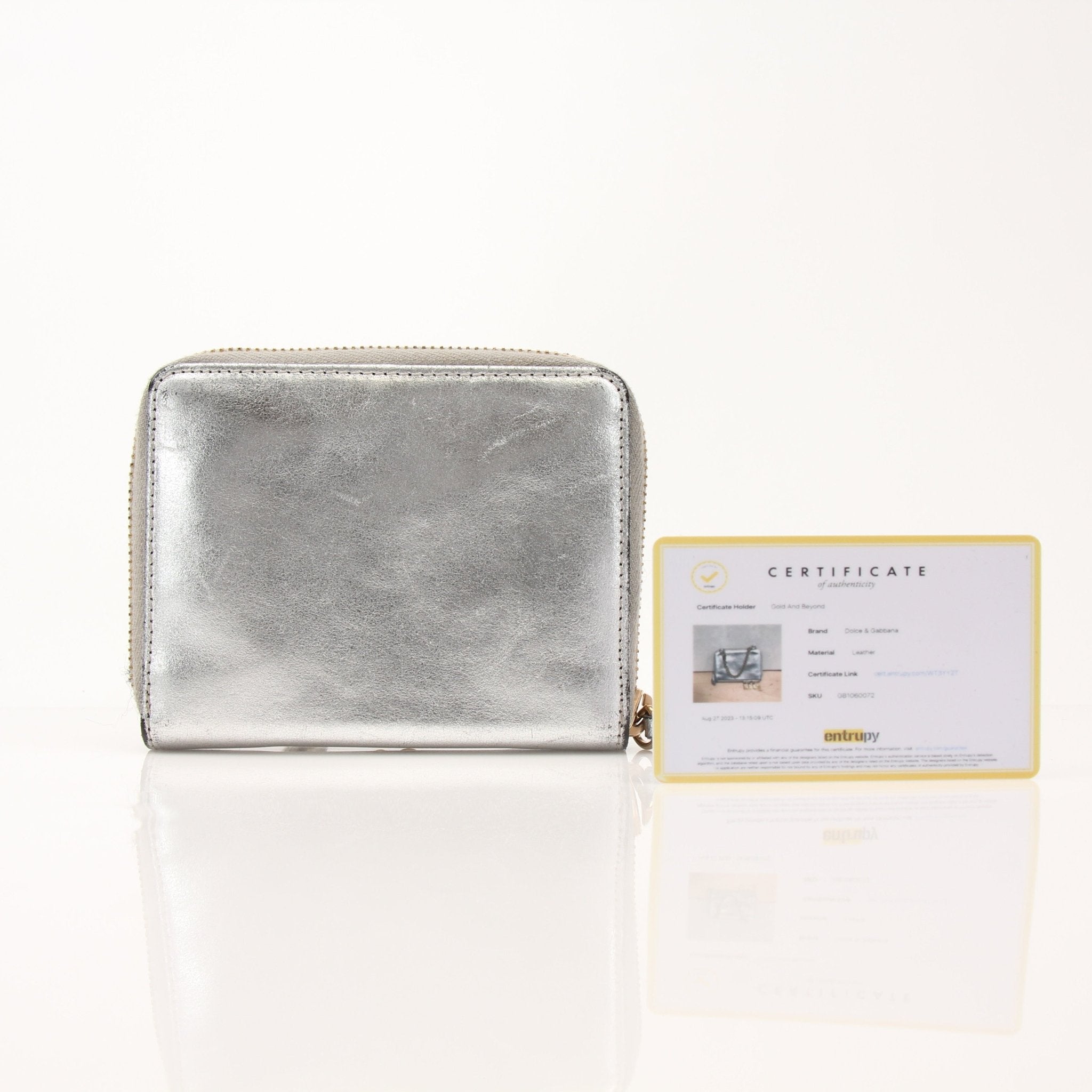 Dolce & Gabbana metallic silver zip-around wallet with gold accents, showcasing its sleek, shiny finish and compact design.