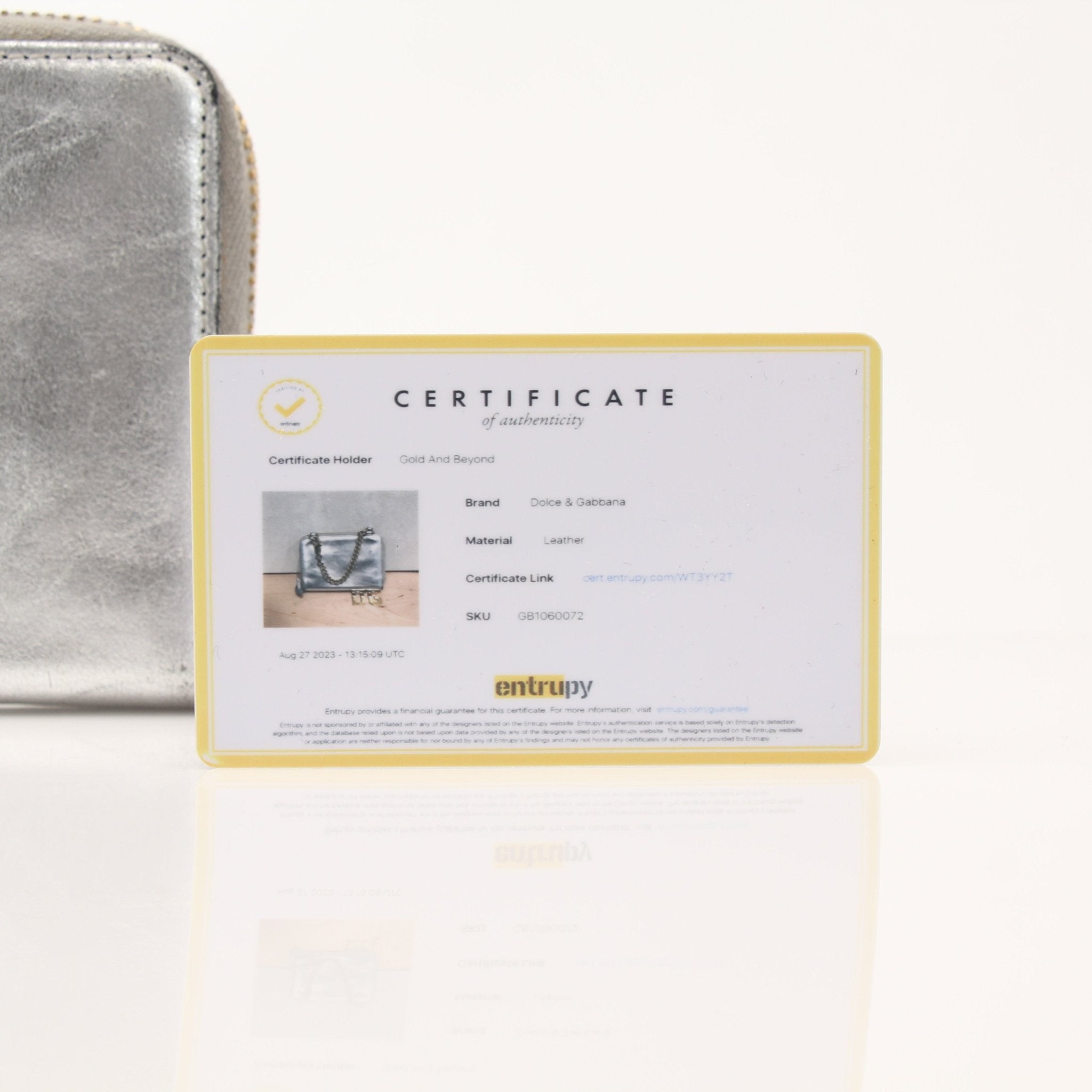 Dolce & Gabbana metallic silver zip-around wallet with textured finish and gold-tone zipper detailing.