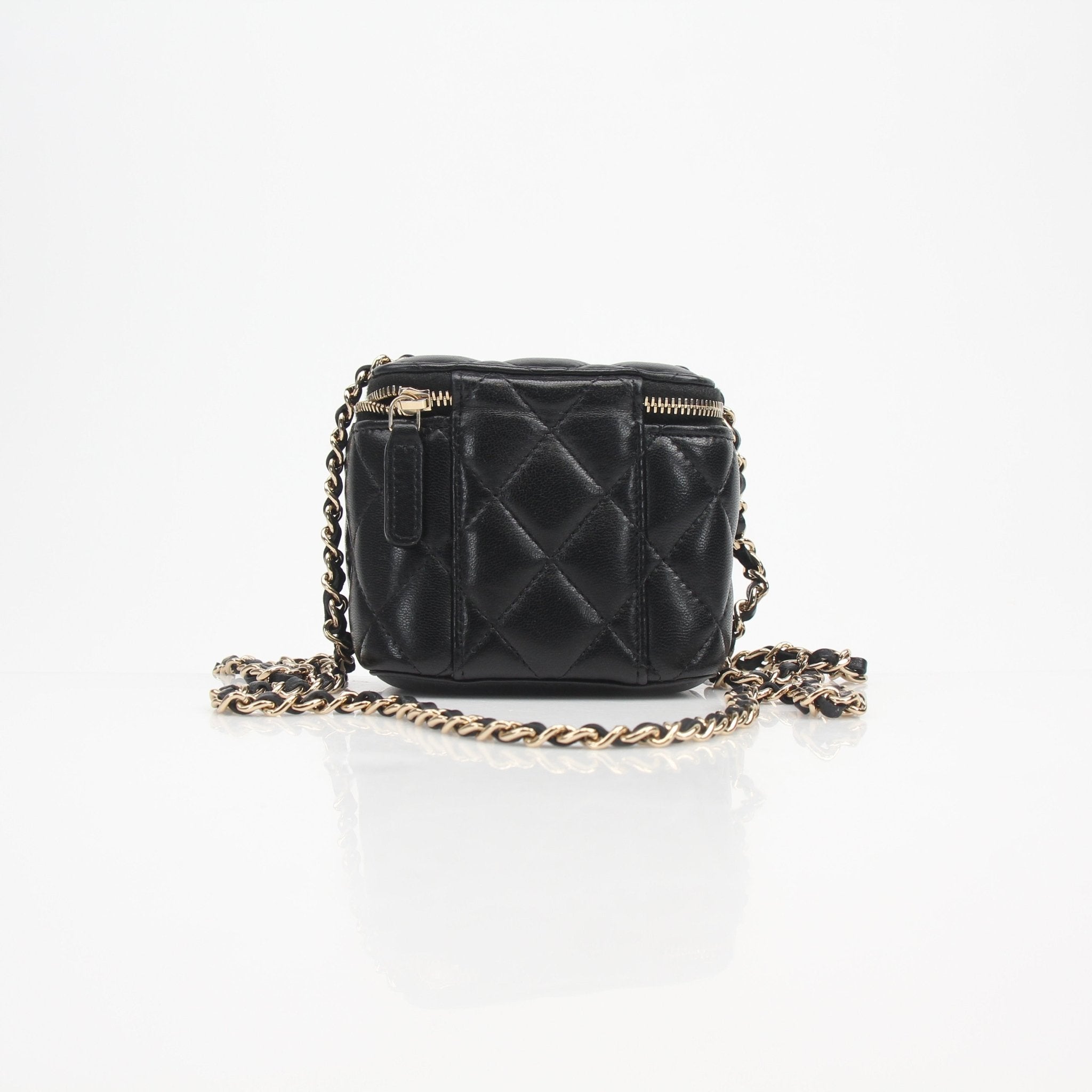 Chanel mini quilted lambskin vanity case with chain strap, black textured leather, gold hardware, and compact design.