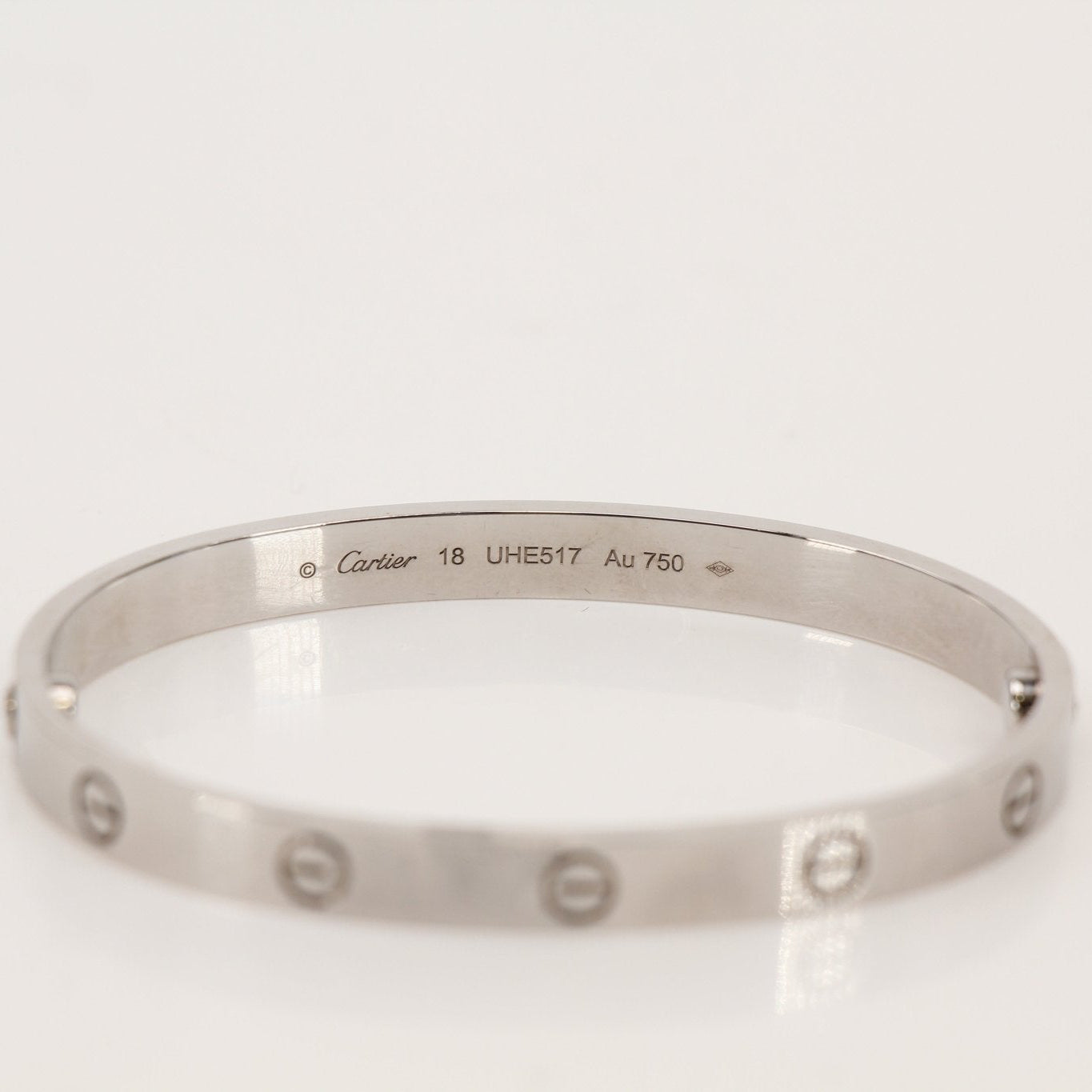 Gold & Beyond Cartier Love Bracelet jewelry featuring a sleek gold band with signature screw motifs on a white background.