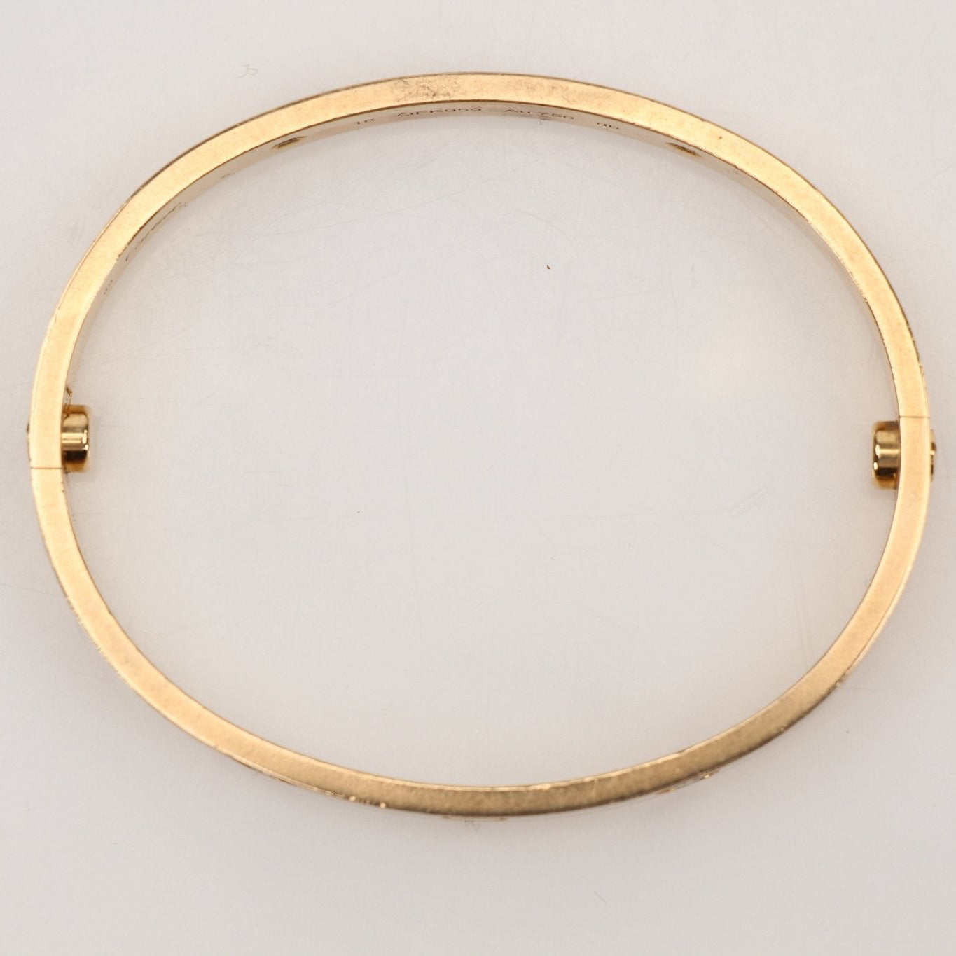 Cartier Diamond Love cuff bracelet with gold band and sparkling diamonds, elegant jewelry piece on a neutral background.