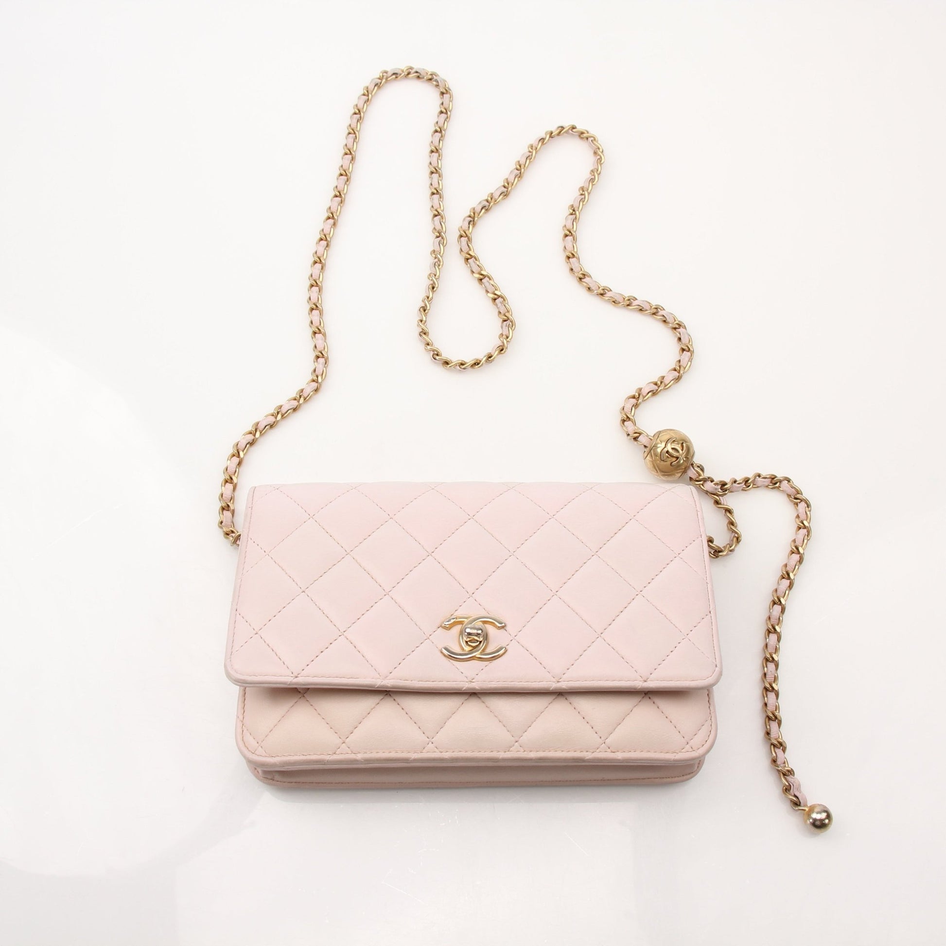 Pink Chanel wallet on chain with gold accents, featuring a compact design and sleek leather finish.