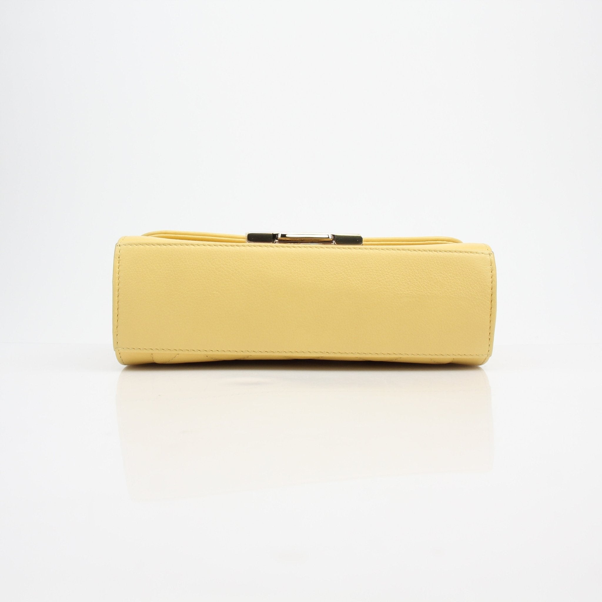 Yellow quilted calfskin Chanel handbag with top handle and flap closure, featuring a classic design and gold chain strap.