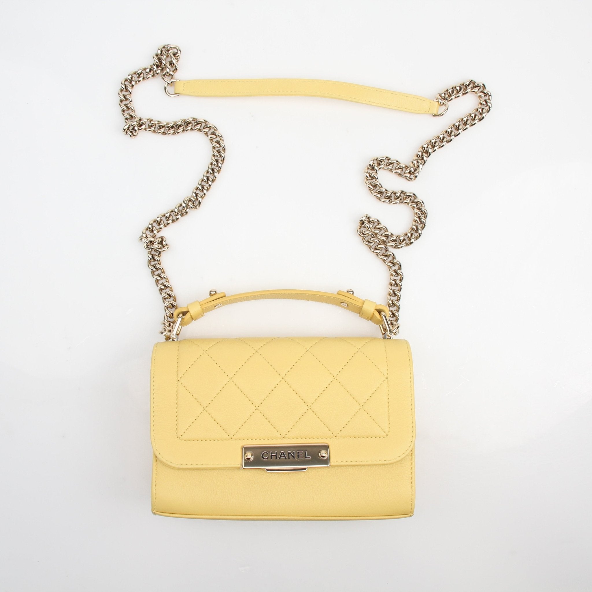 Yellow quilted calfskin Chanel handbag with top handle and flap closure, featuring gold accents and a classic textured design.