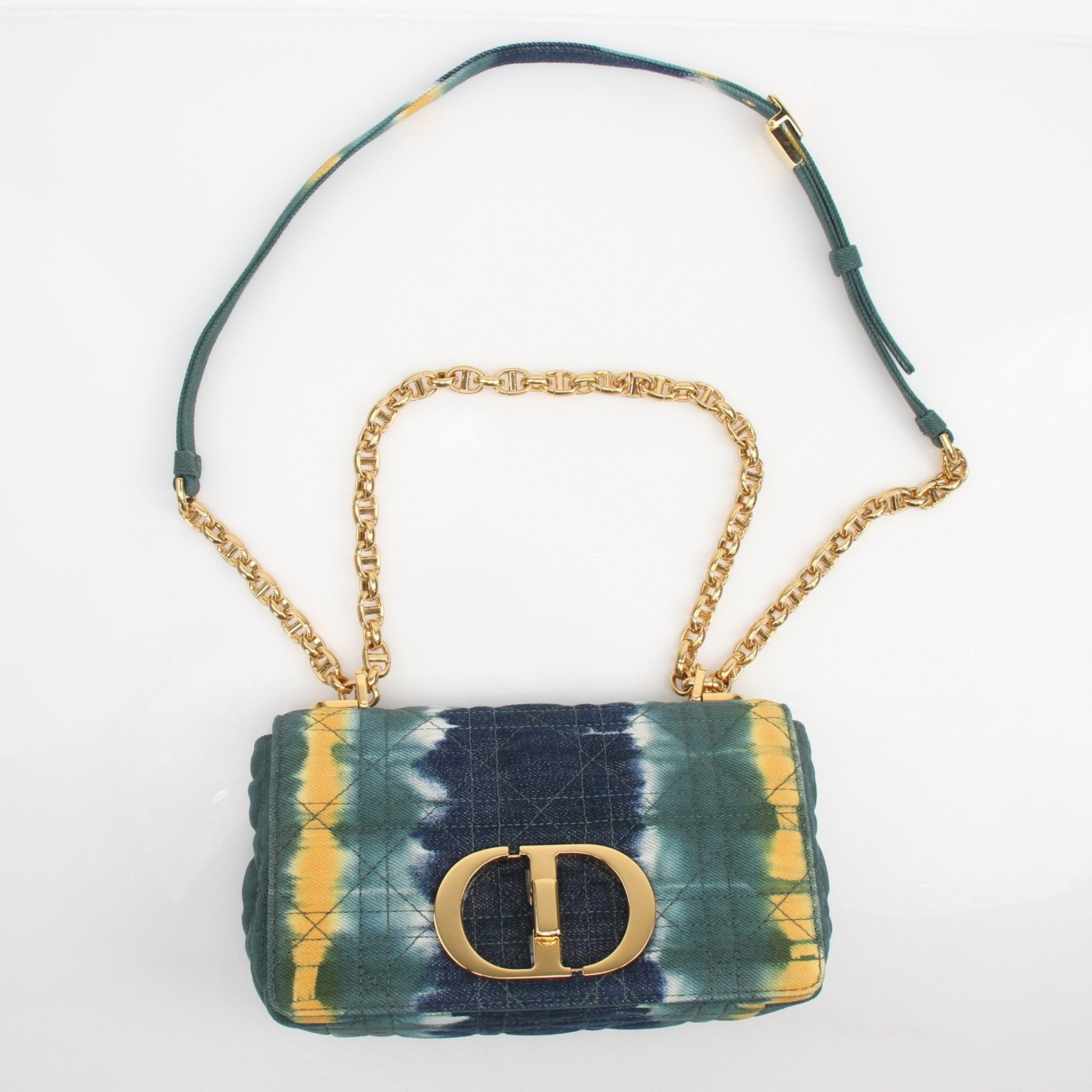 Christian Dior Caro small tie-dye denim shoulder handbag with gold hardware and a chain strap, displayed on a neutral background.