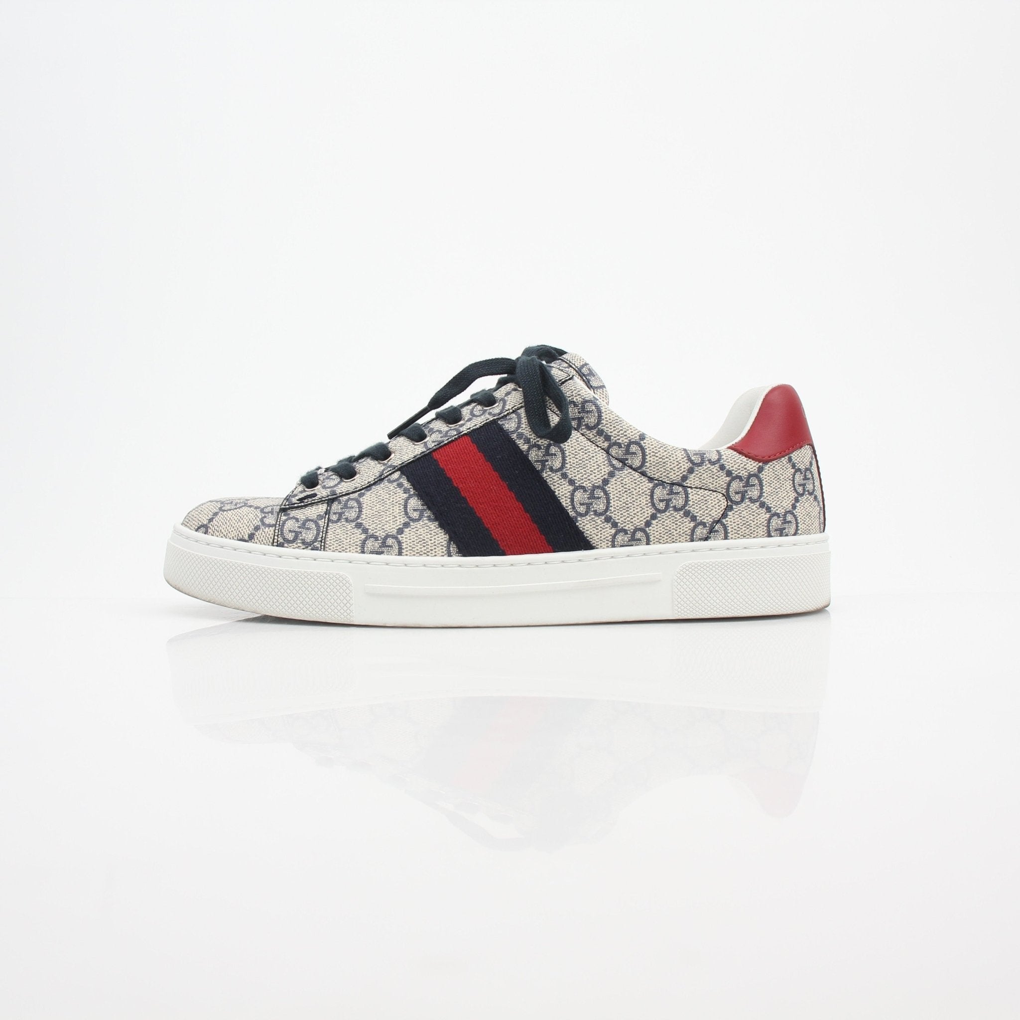 Gucci women's Ace GG Supreme monogram web sneakers featuring white leather, signature gold accents, and rubber sole.