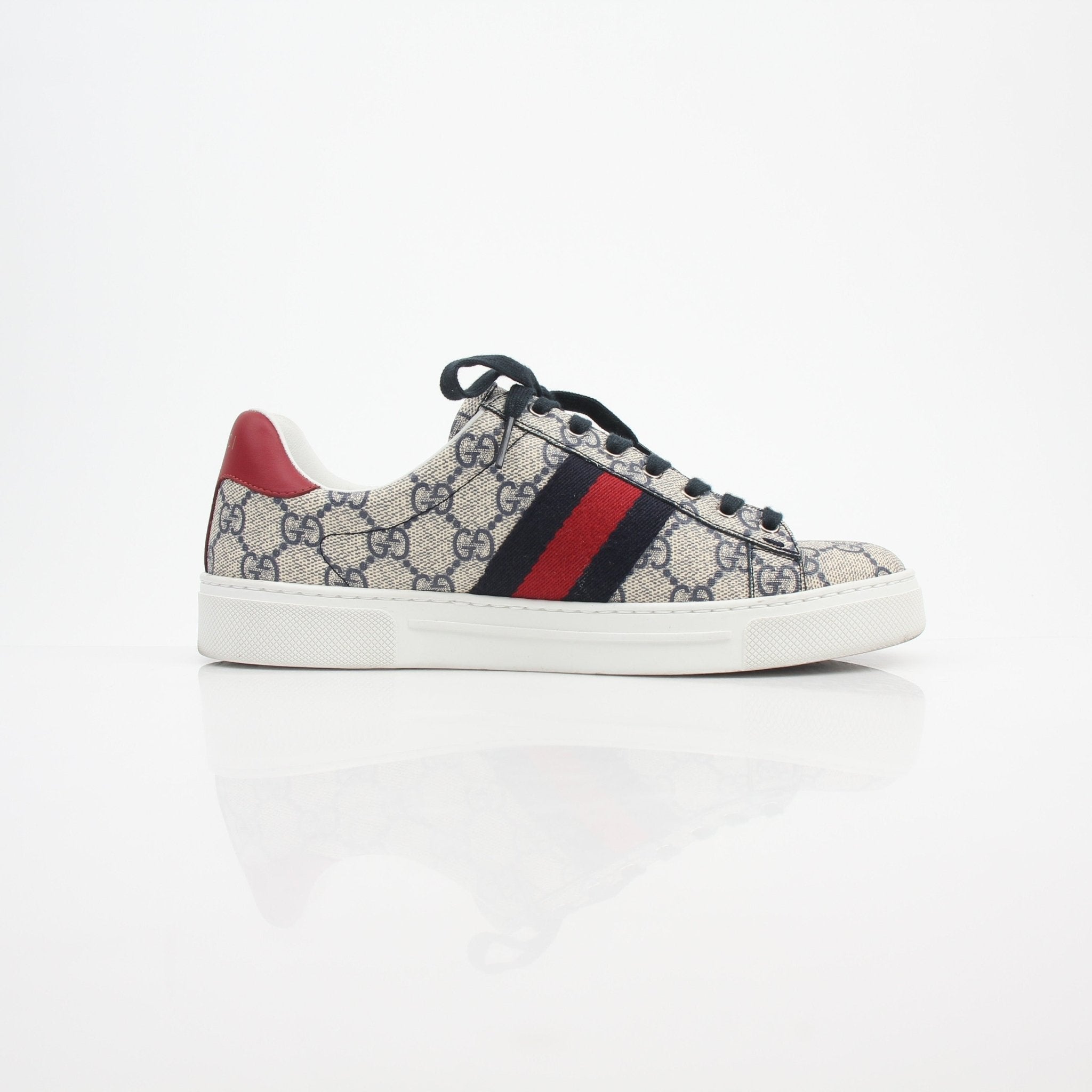 Gucci women’s Ace GG Supreme monogram web sneakers with white rubber soles and signature design details, worn on a model.