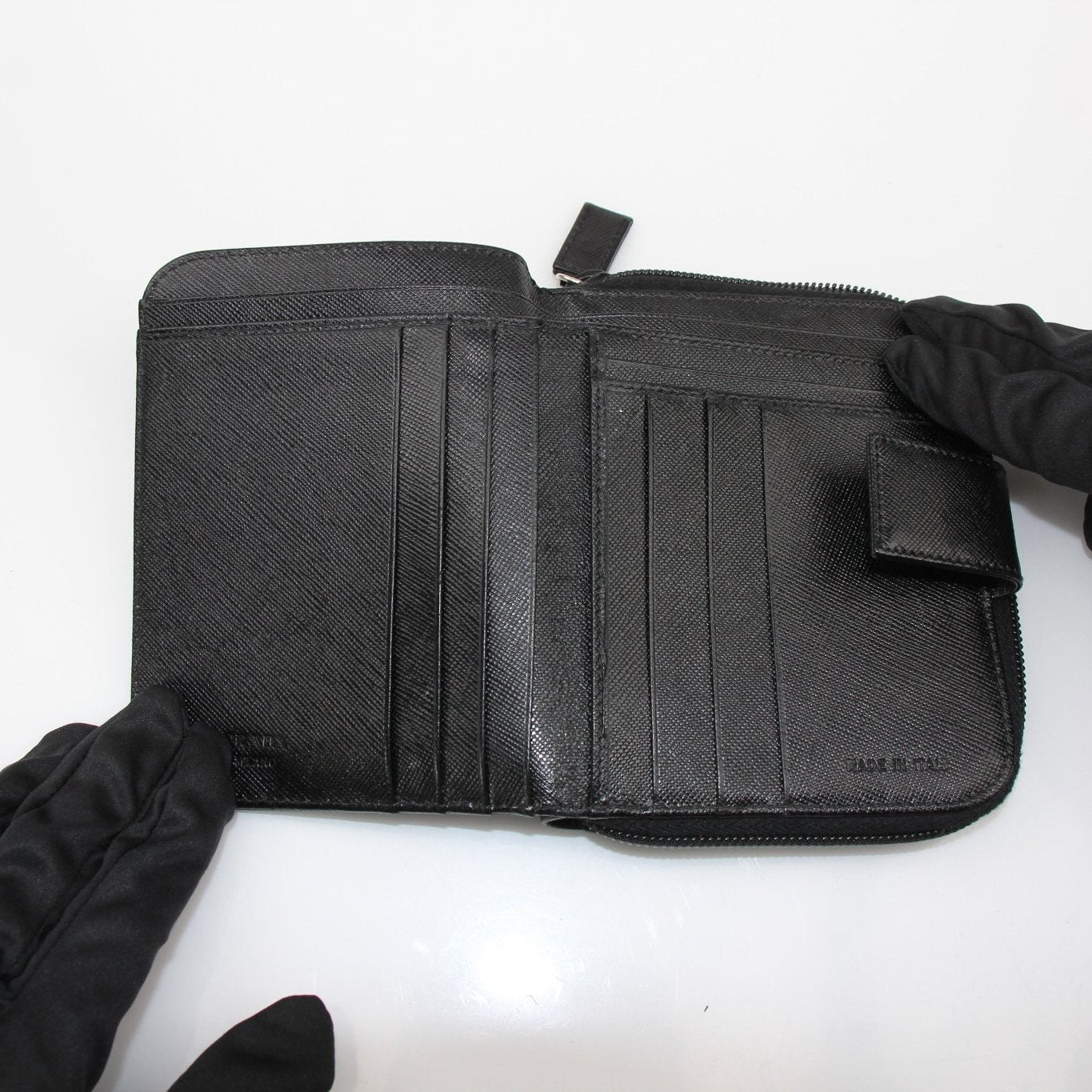 Gold &amp; Beyond Prada zip wallet showing sleek leather exterior with gold zipper and compact design.