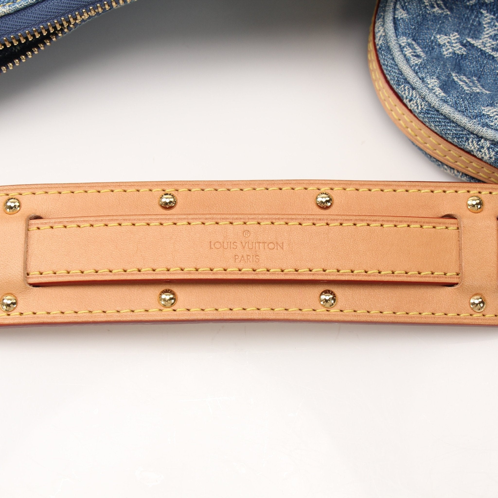 Louis Vuitton denim croissant handbag with gold hardware, stylishly displayed with a soft, textured fabric exterior.
