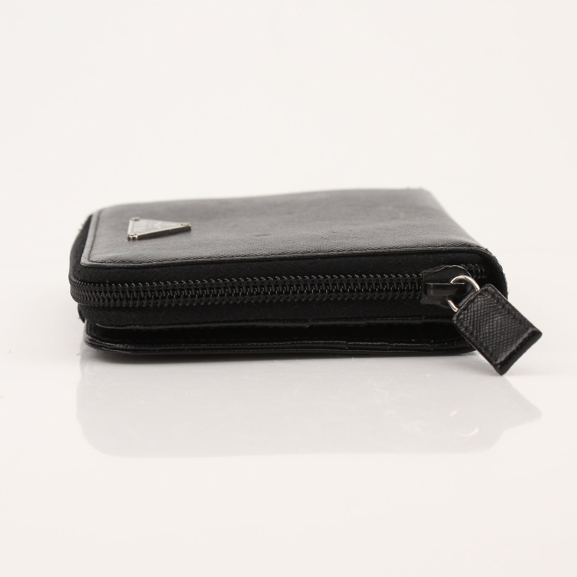 Prada zip wallet in black leather with gold-tone zipper and branding, featuring multiple card slots and a sleek design.