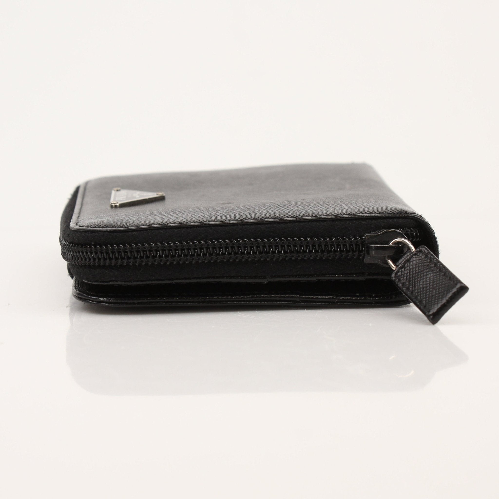 Prada zip wallet in black leather with gold-tone zipper and branding, featuring multiple card slots and a sleek design.