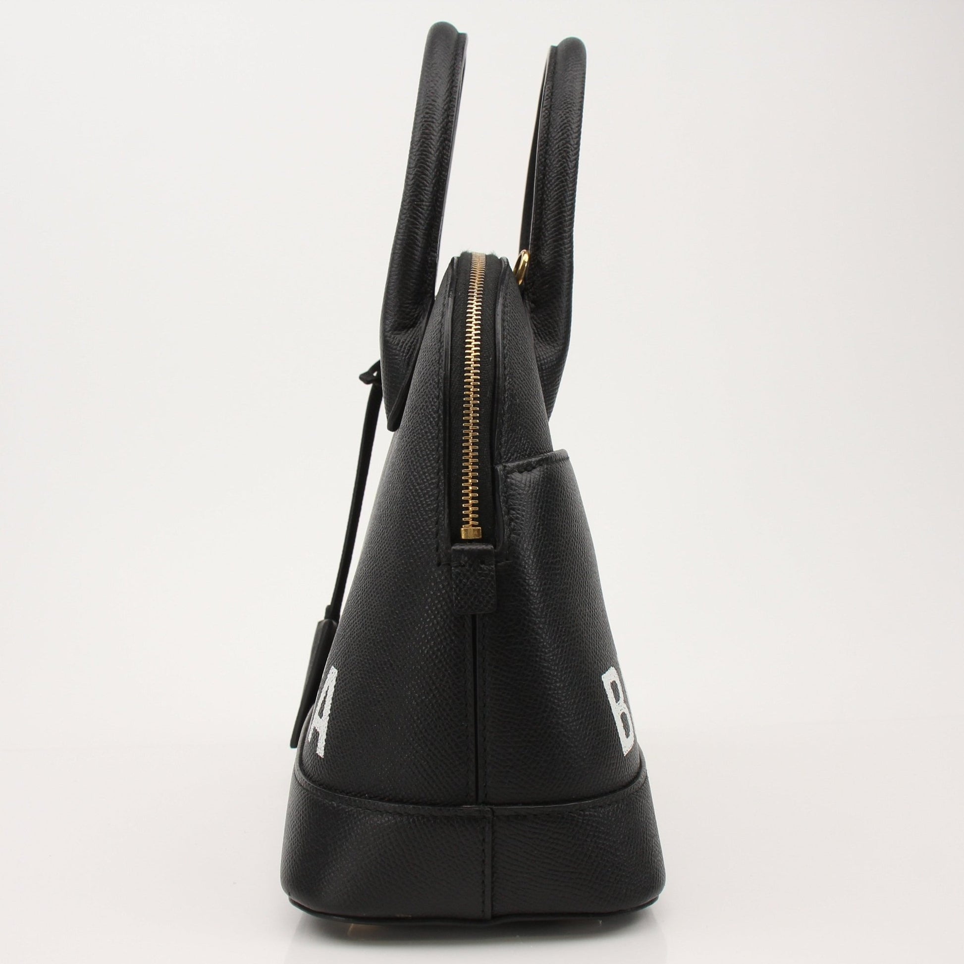 Gold & Beyond Balenciaga Ville top handle handbag with structured design and gold-tone hardware on a plain background.