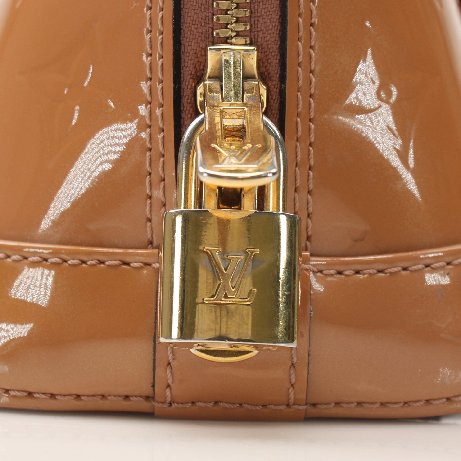 Louis Vuitton Rose Vernis Alma BB handbag with gold hardware and structured design, showcasing its glossy finish and elegant appearance.