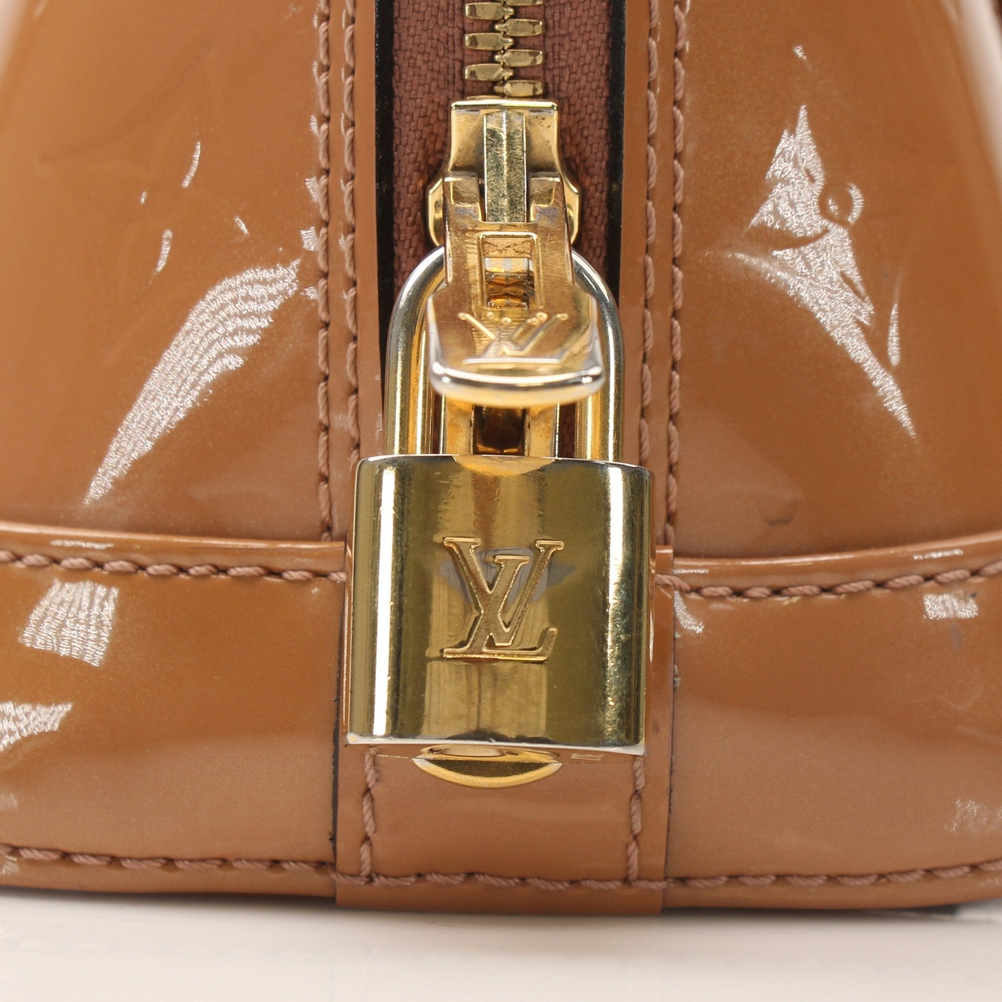 Louis Vuitton Rose Vernis Alma BB handbag with gold hardware and structured design, showcasing its glossy finish and elegant appearance.