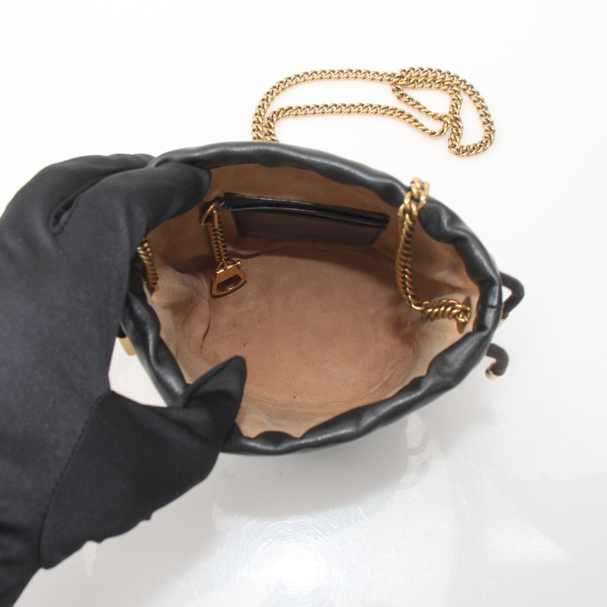 Gucci GG Marmont small bucket handbag with gold chain strap and chevron quilted leather design.