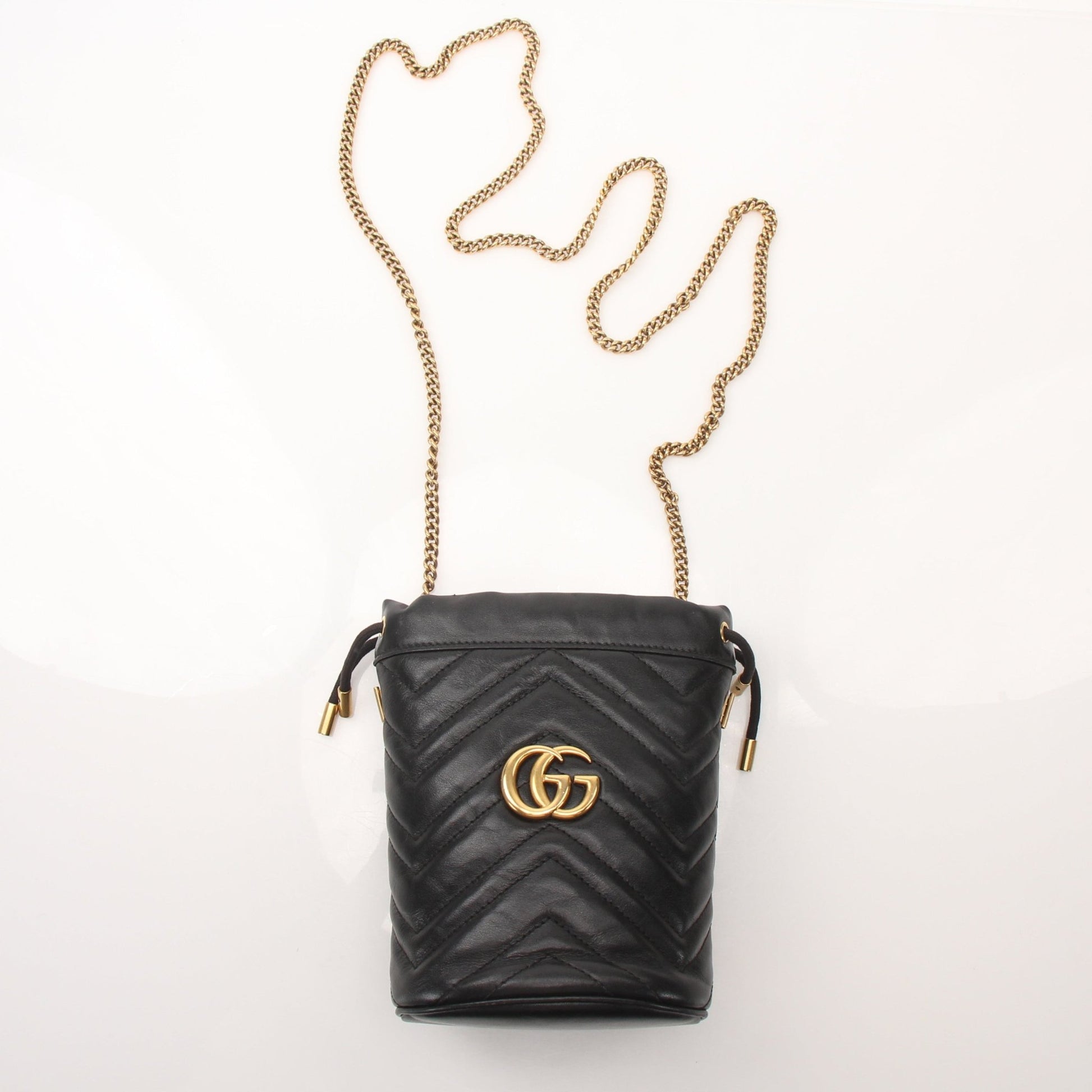 Gucci GG Marmont small bucket handbag in black leather with gold hardware and adjustable strap, displayed on a white background.