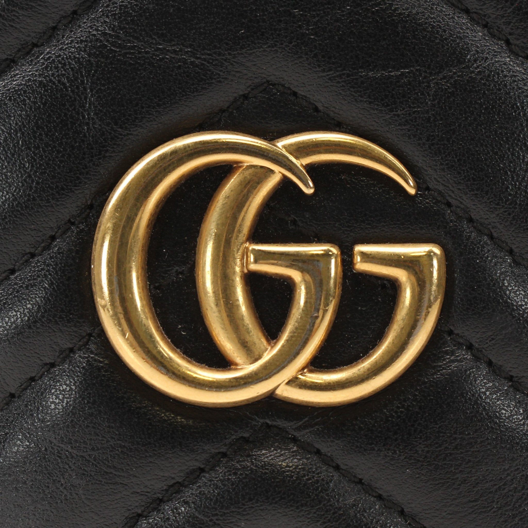 Gucci GG Marmont small bucket handbag in beige leather with gold hardware and chevron quilted design.