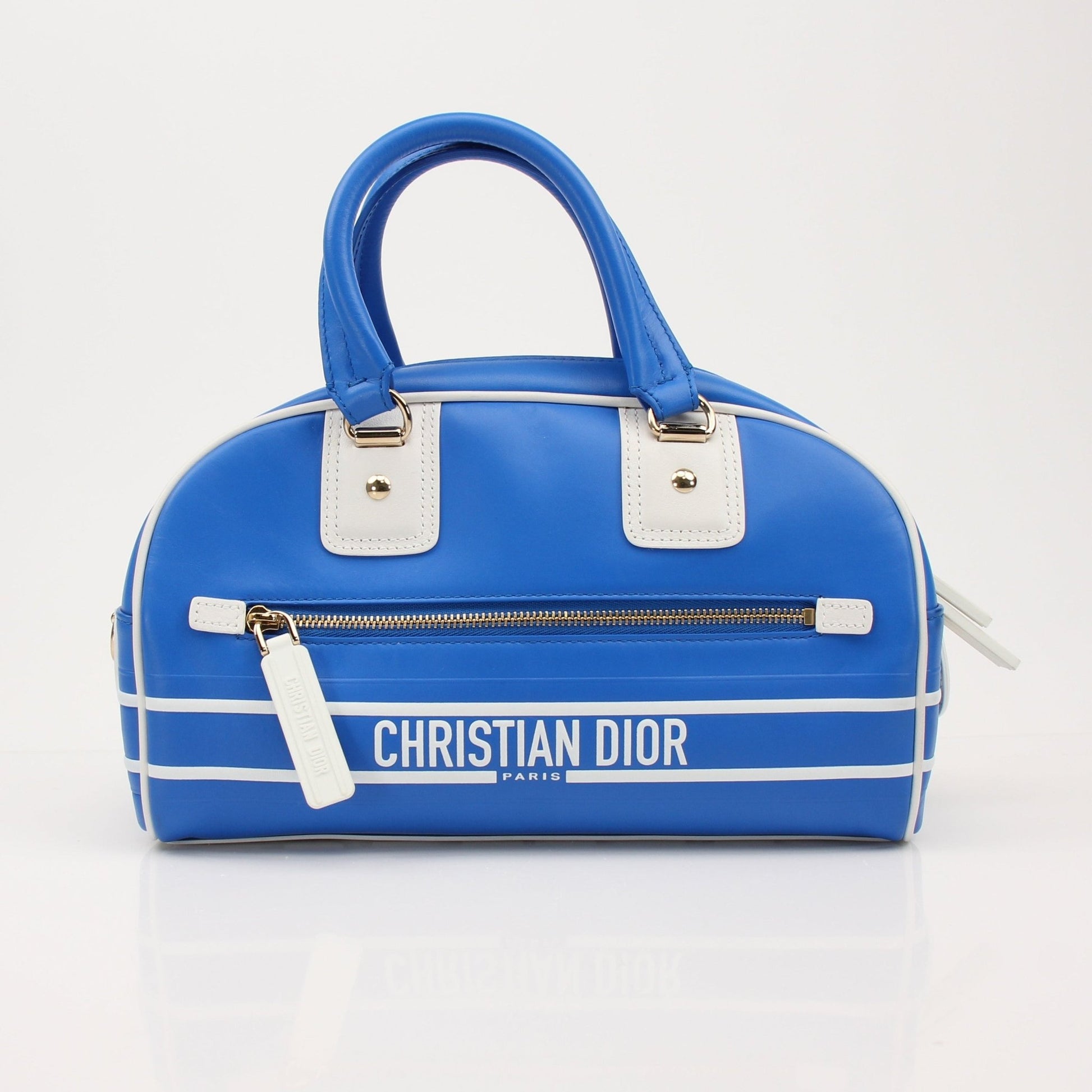 Christian Dior blue bowling handbag with gold accents, featuring a structured design and top handle for a stylish look.