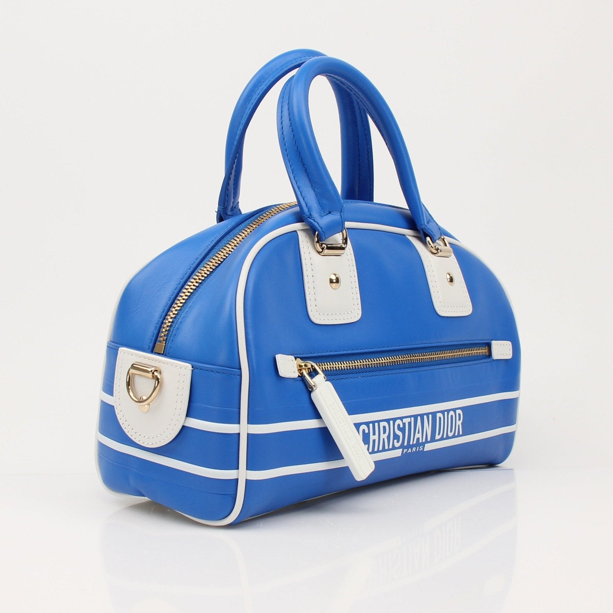 Blue Christian Dior bowling handbag with gold accents, featuring structured design and elegant handles.