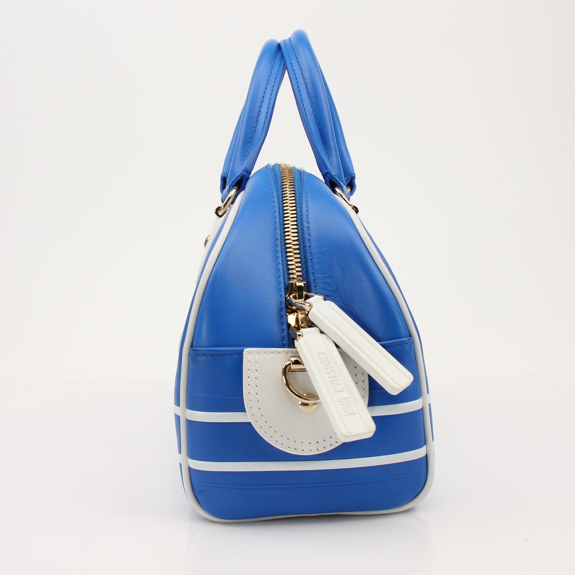 Christian Dior blue bowling handbag with gold accents, stylish designer purse with structured shape and top handles.