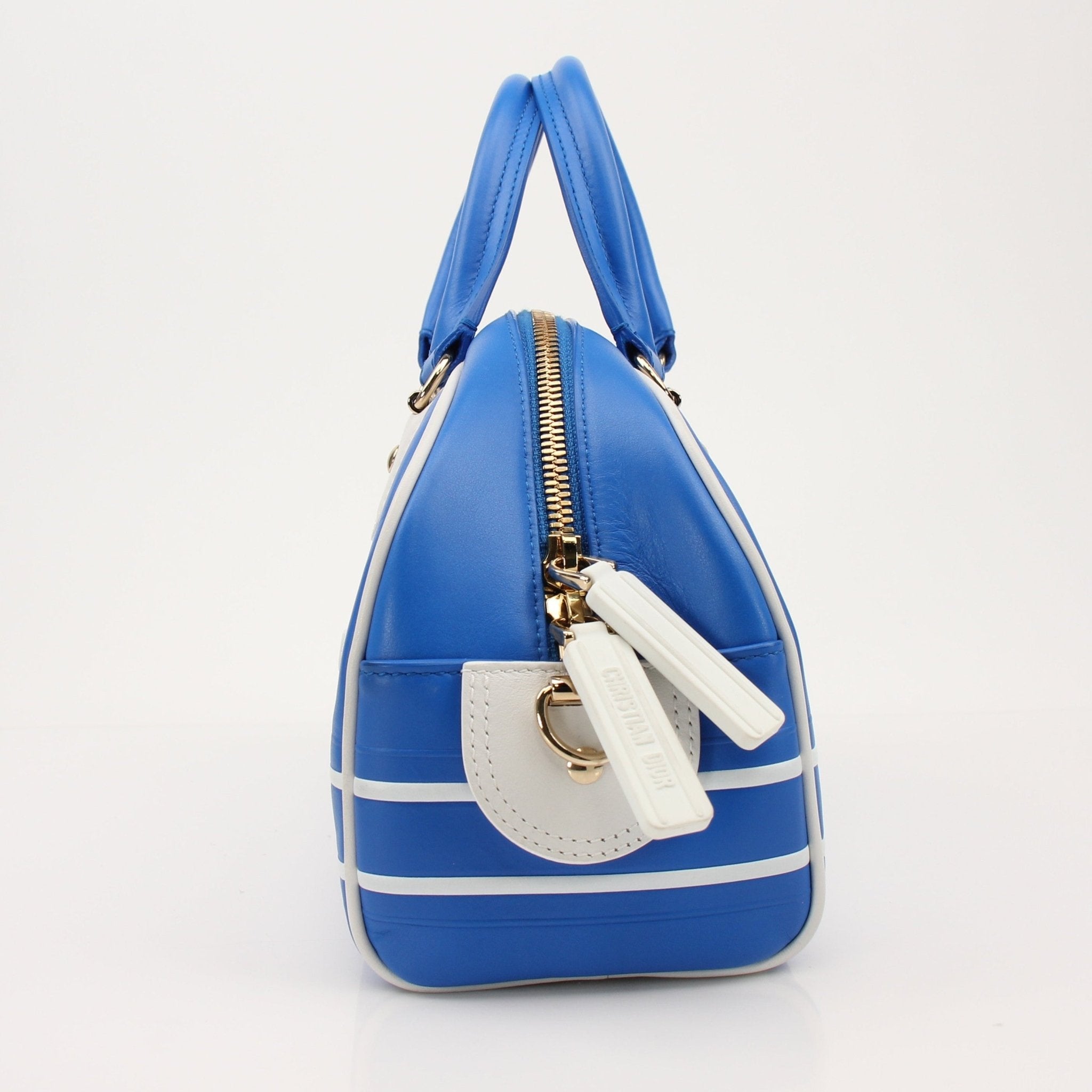 Christian Dior blue bowling handbag with gold accents, stylish designer purse with structured shape and top handles.