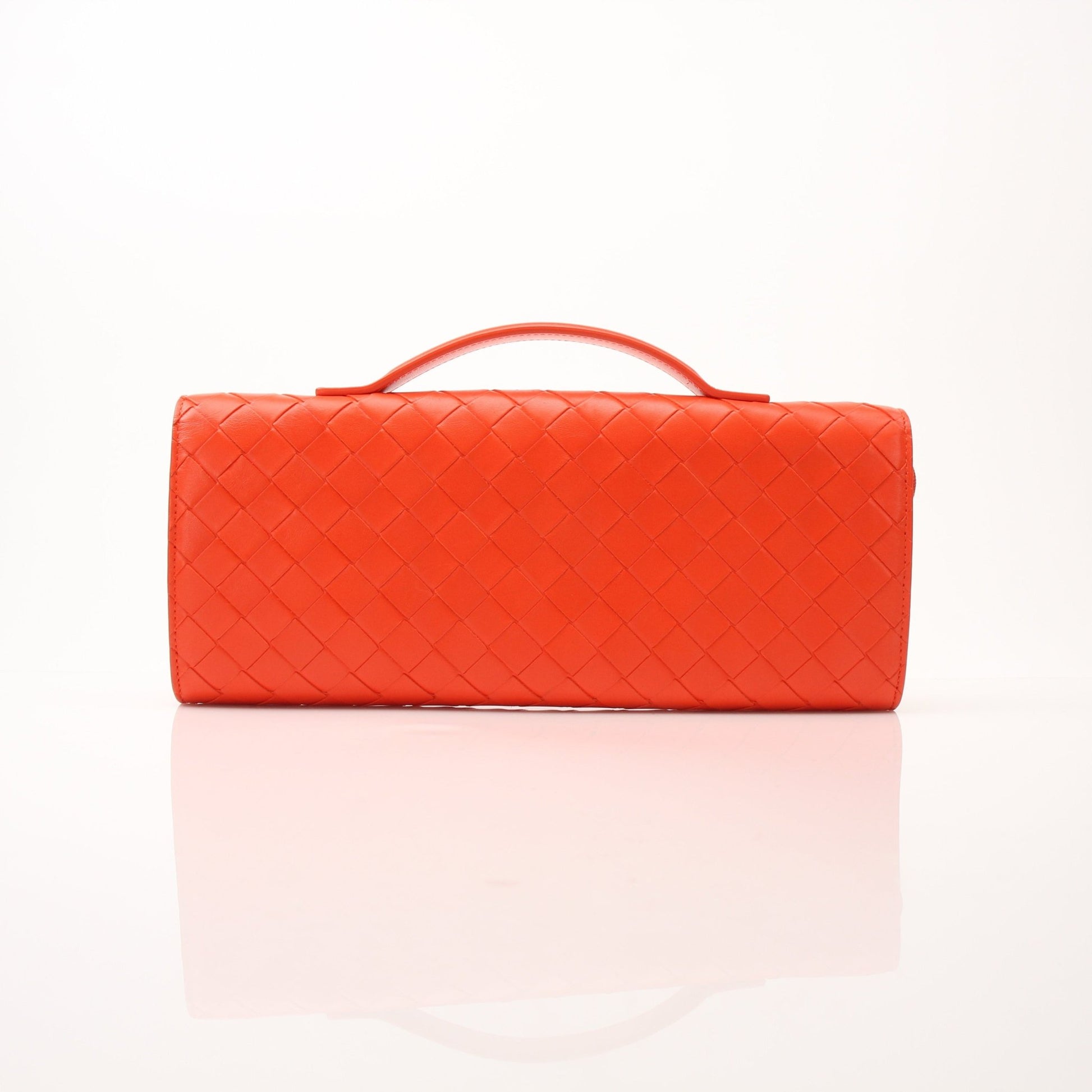 Bottega Veneta Andiamo clutch handbag in gold with woven leather design, held by hand against a neutral background.