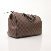 Louis Vuitton Speedy 30 handbag in classic monogram canvas with leather handles and gold-tone hardware on a neutral background