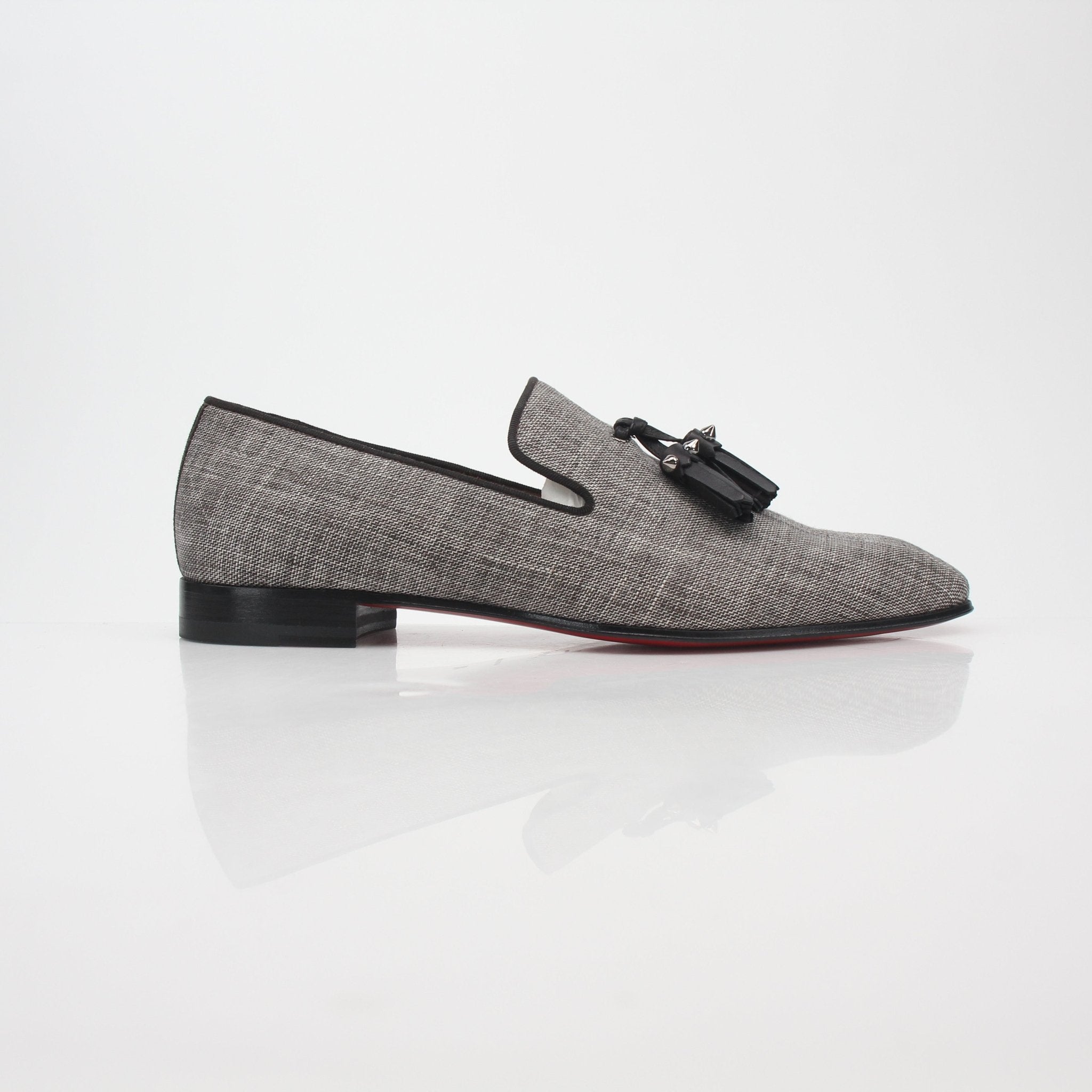 Gray Christian Louboutin Dandelion Spikes Tassel Loafers with tassel detailing and spike embellishments, stylish shoes on a neutral background.