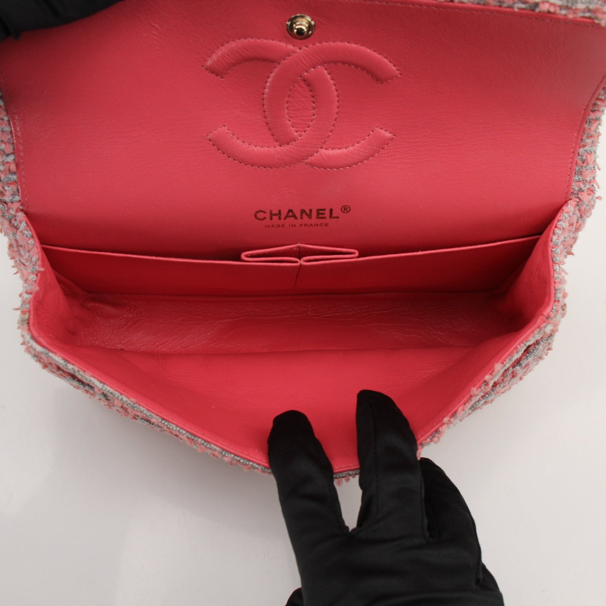 Pink tweed Chanel flap handbag with gold chain strap and classic design, stylish accessory for any outfit.