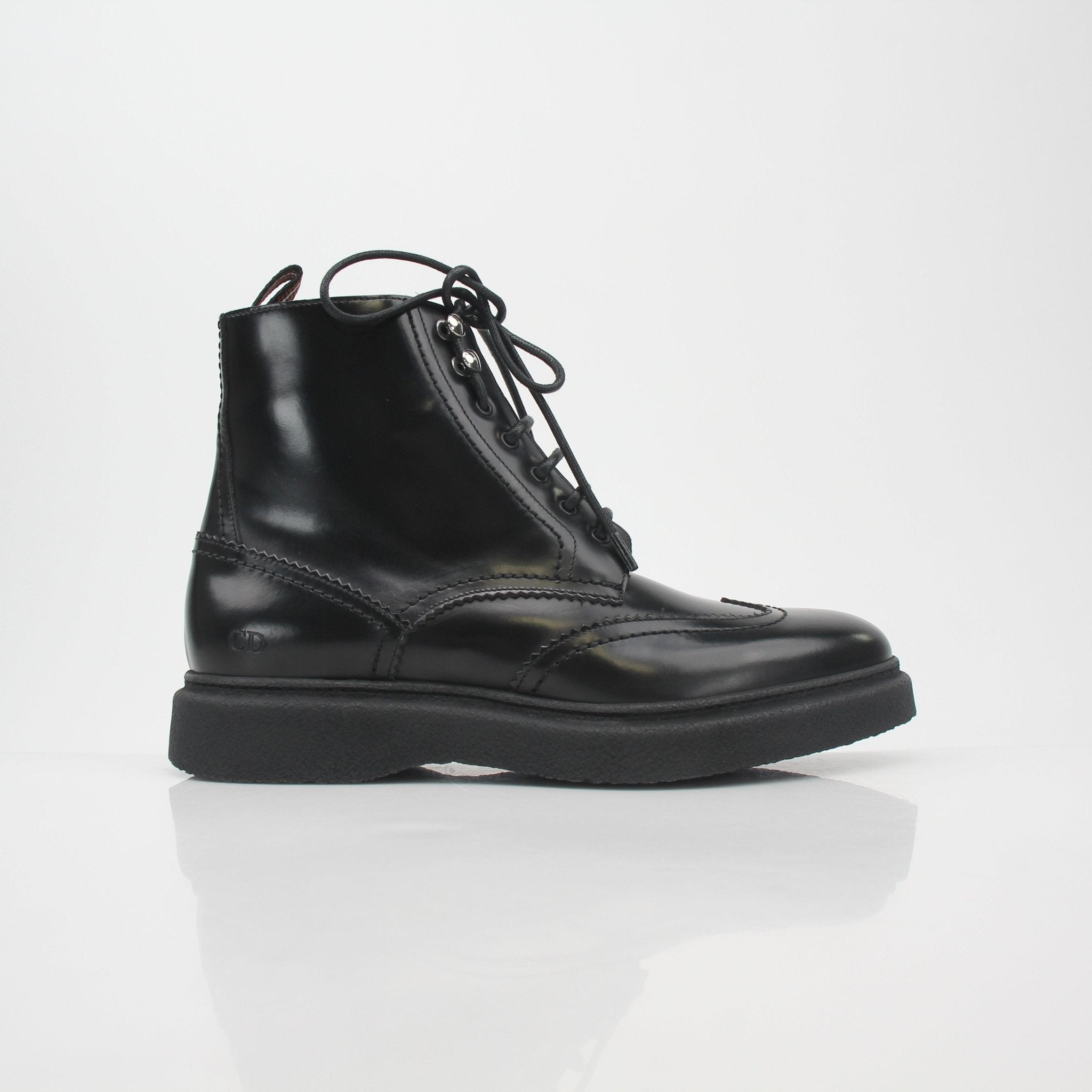 Christian Dior black leather wingtip combat ankle boots with laces and chunky soles, styled as fashion-forward shoes by Gold & Beyond.